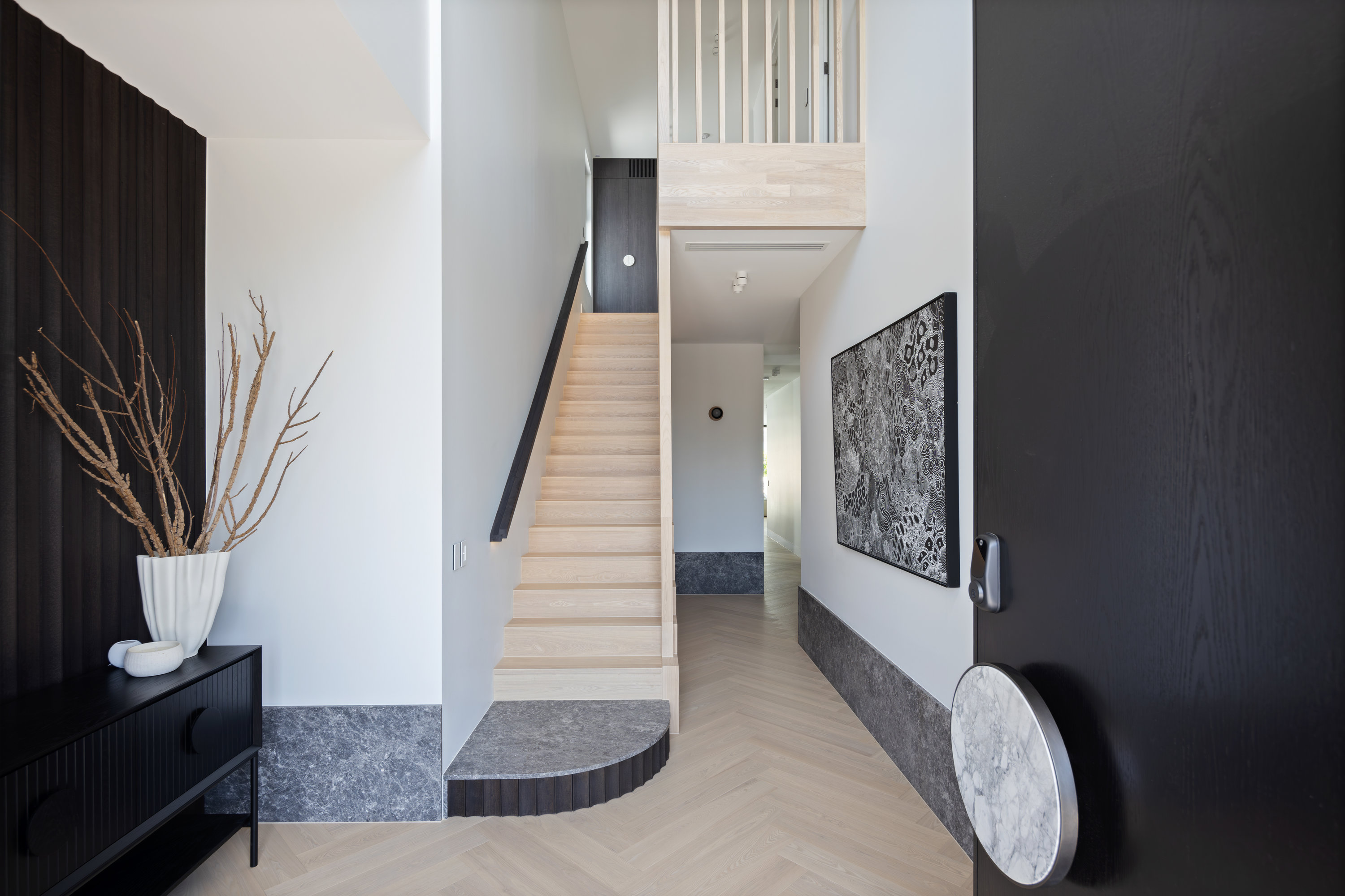 Entry hall with oak stair, black handrail and curved stone step at 9 Netherby