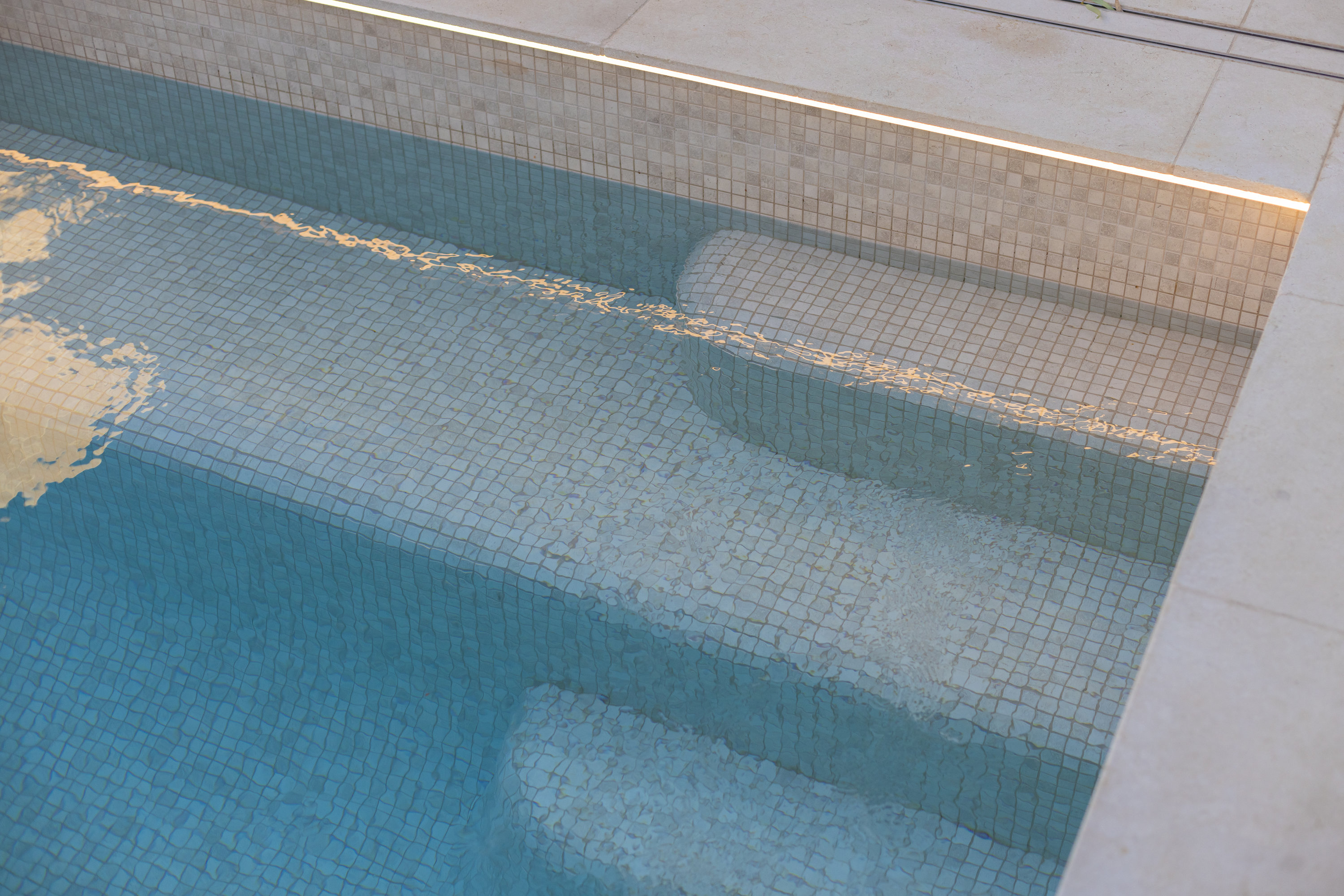 Mosaic-tiled pool steps with a stone coping edge at 9 Netherby