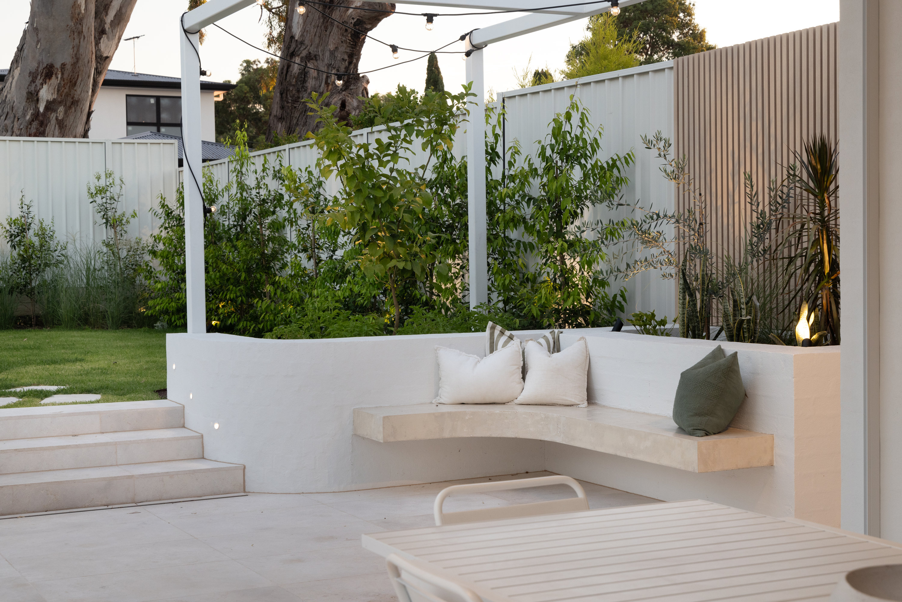 Built-in outdoor bench seating beneath festoon lighting in the rear garden at 9 Netherby