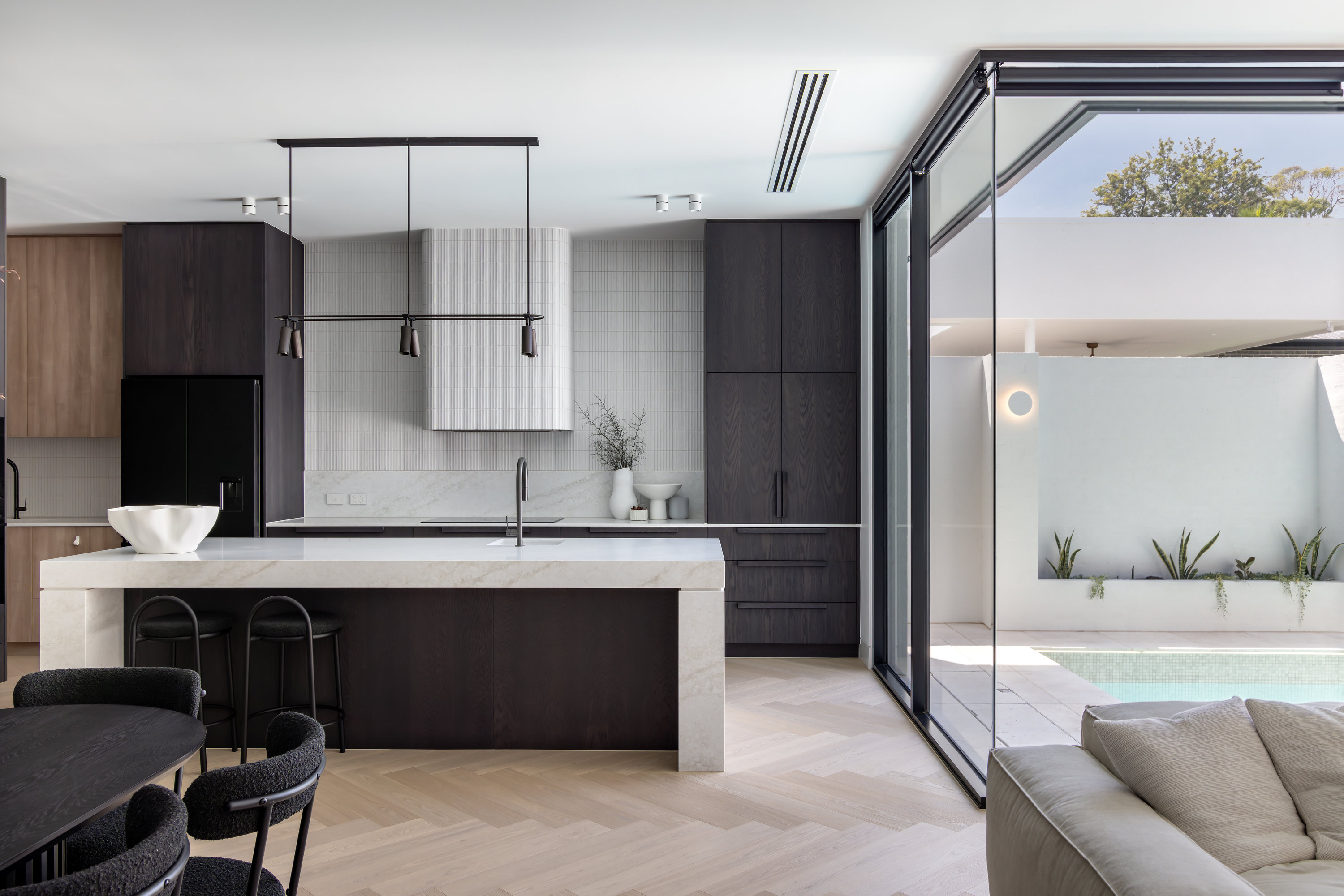 Kitchen and dining opening to the pool through black-framed glazing at 9 Netherby