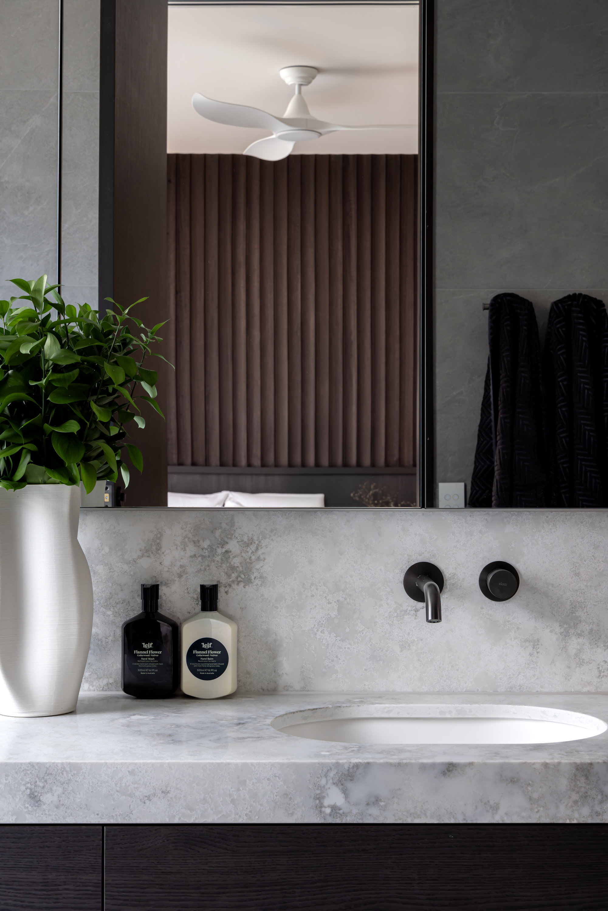 Ensuite vanity with stone benchtop, black tapware and full-height mirror at 9 Netherby