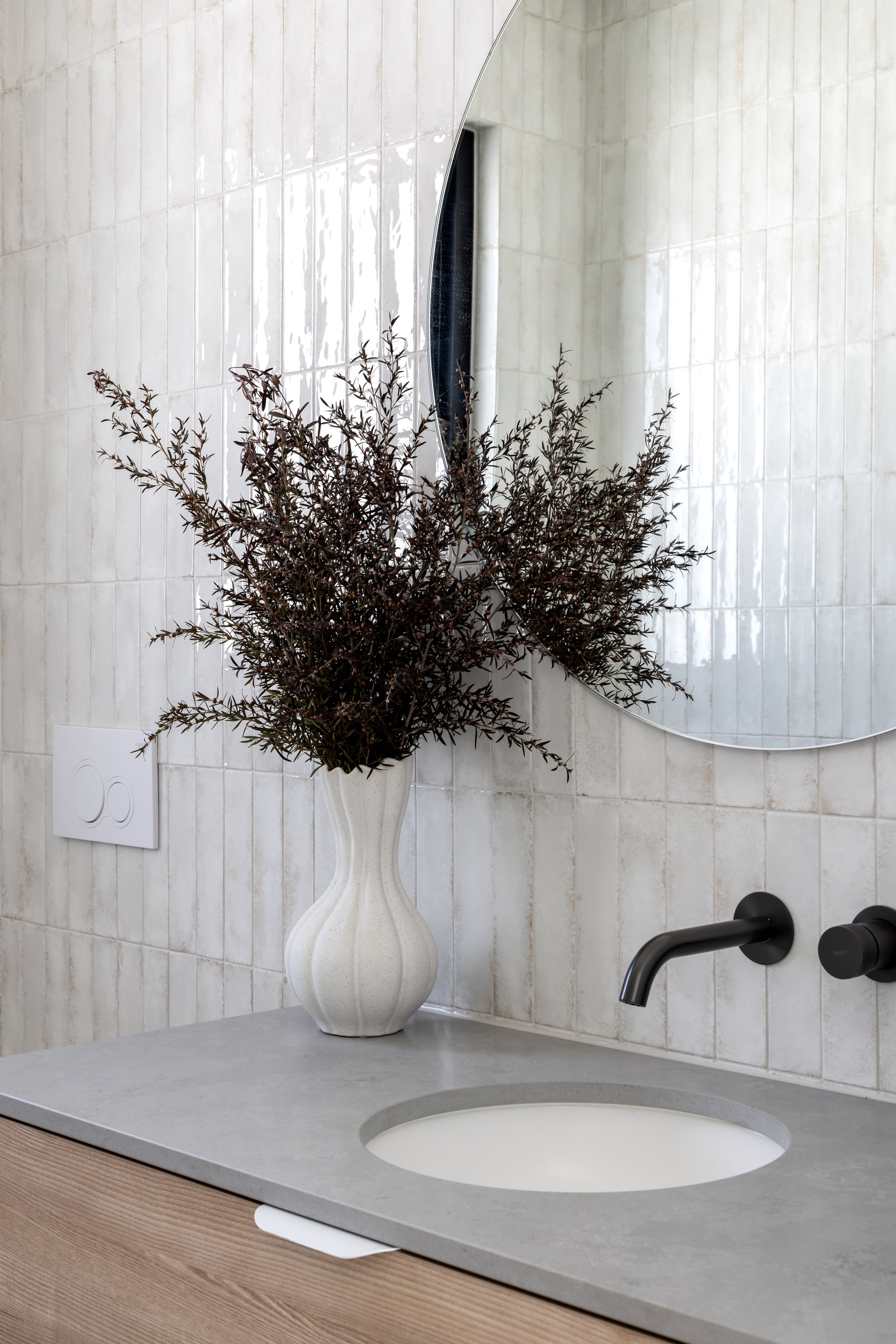 Powder room vanity with a round mirror, glazed tiles and black wall tapware at 9 Netherby