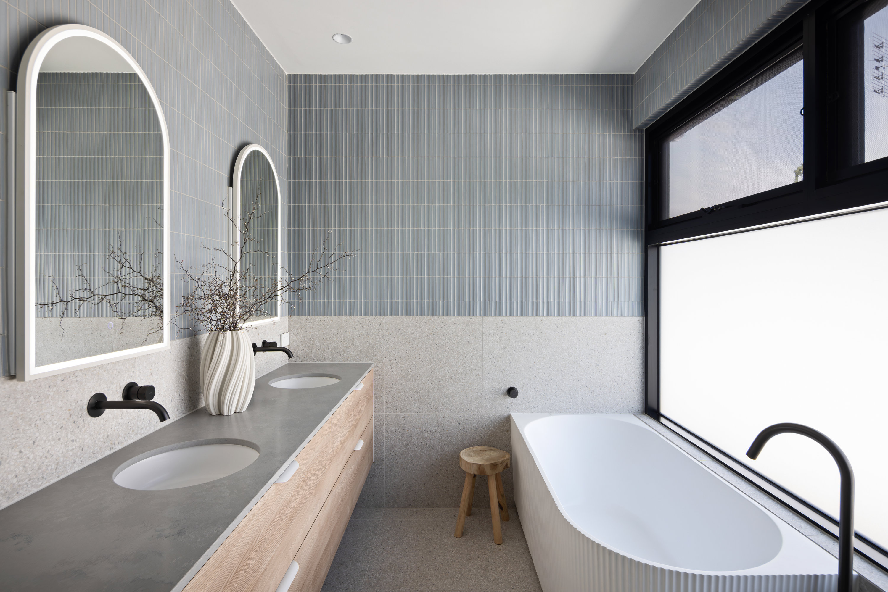 Family bathroom with twin arched mirrors, oak double vanity and a fluted freestanding bath at 9 Netherby