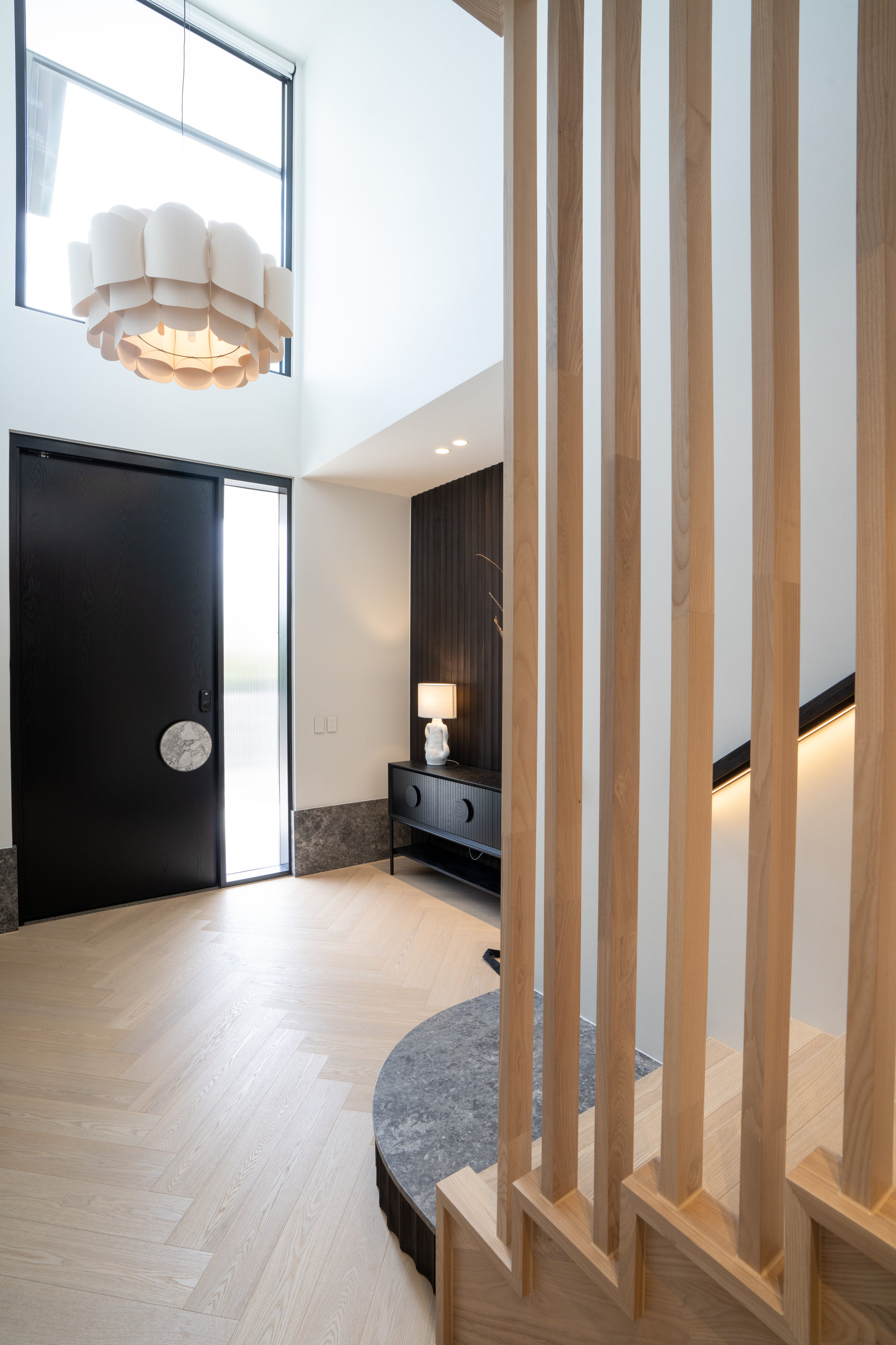 Double-height entry with sculptural pendant, herringbone oak flooring and timber batten screen at 9 Netherby