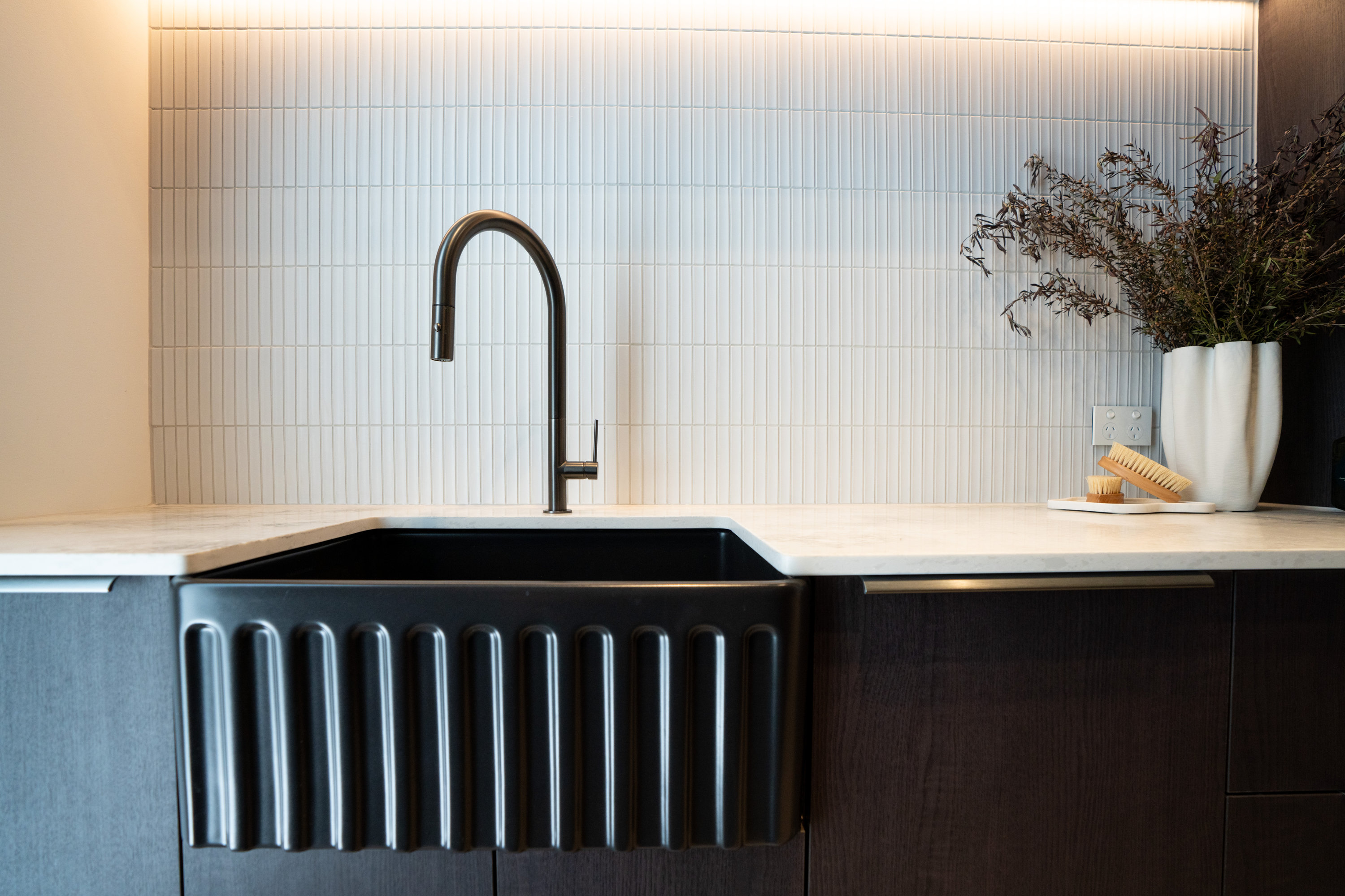 Fluted black apron sink with black tapware and a white finger-tile splashback at 9 Netherby