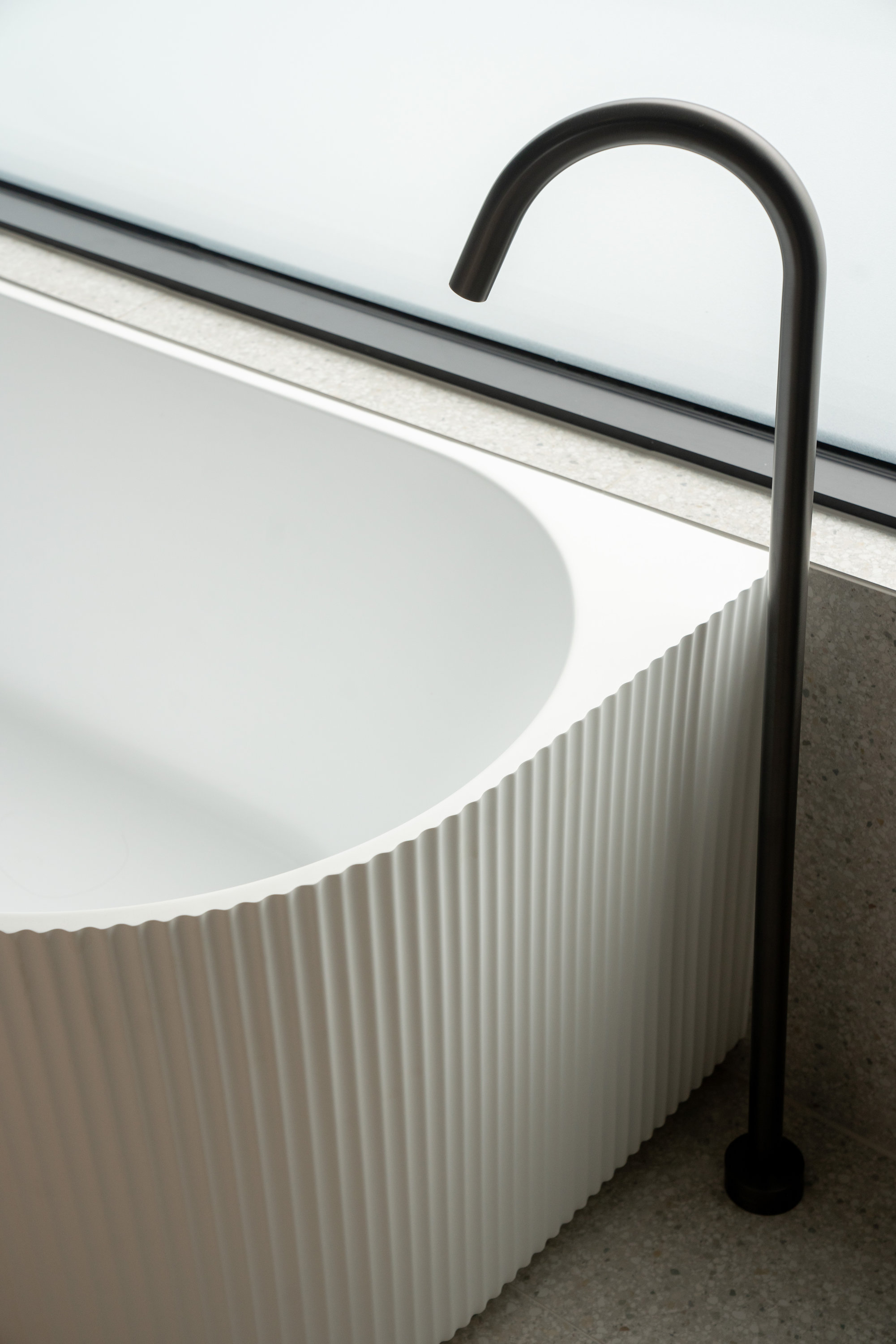 Fluted freestanding bath with black floor-mounted bath filler on terrazzo at 9 Netherby