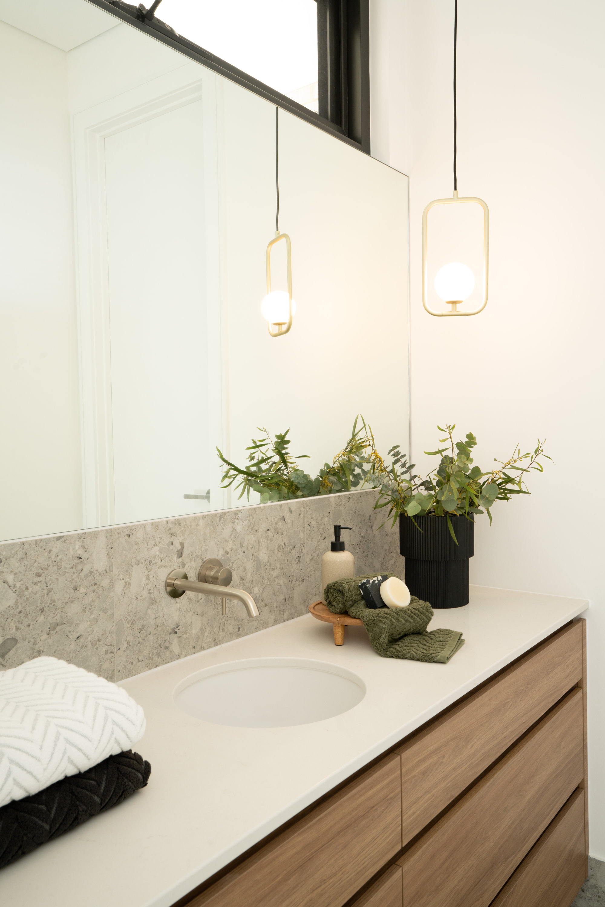 Bathroom vanity with terrazzo splashback, brass pendant and timber joinery at 24 Wattle Park