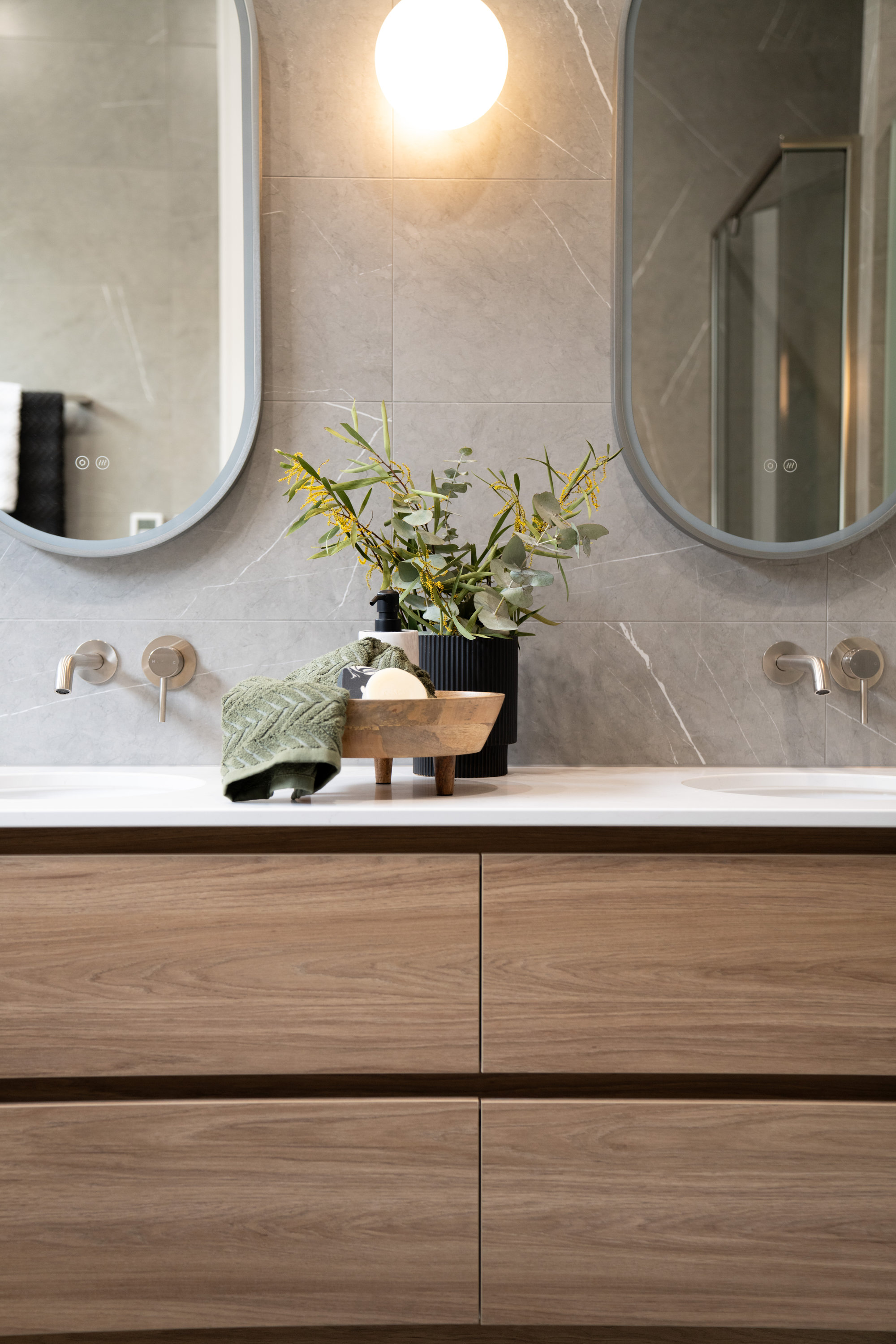 Ensuite with twin oval mirrors, stone-look tiling and a timber double vanity at 24 Wattle Park