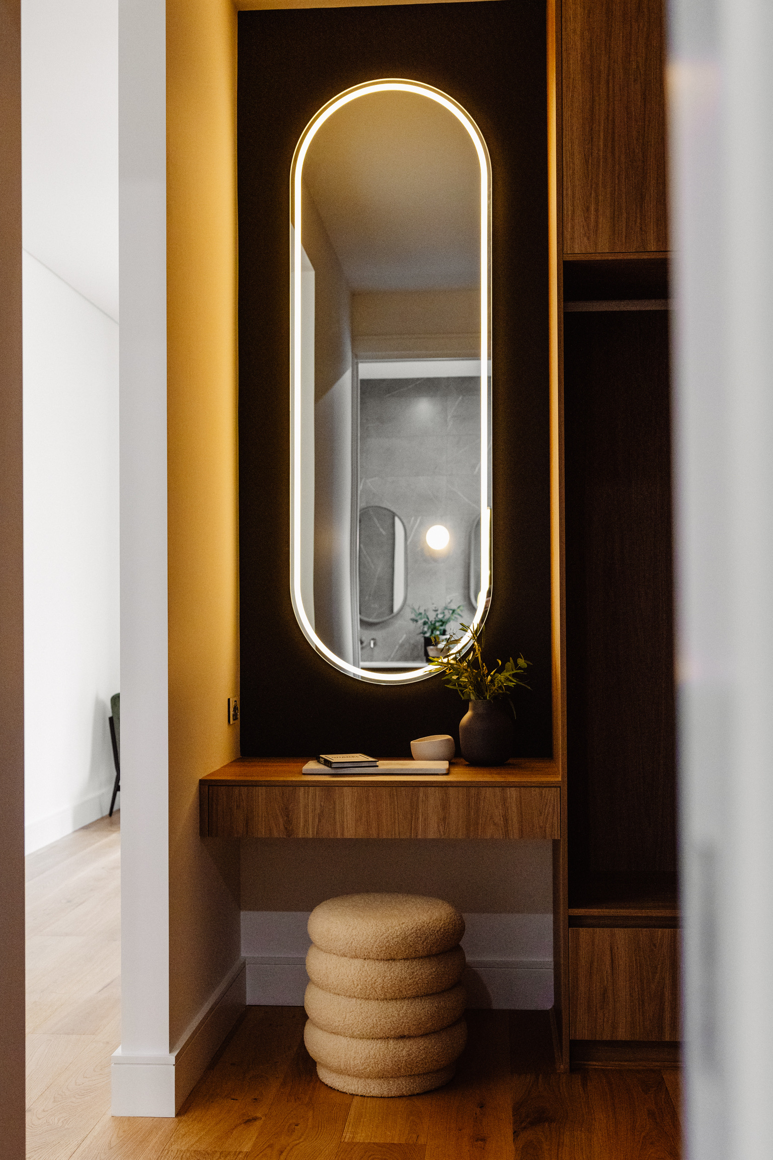 Dressing nook with a backlit oval mirror, timber console and boucle stool at 24 Wattle Park
