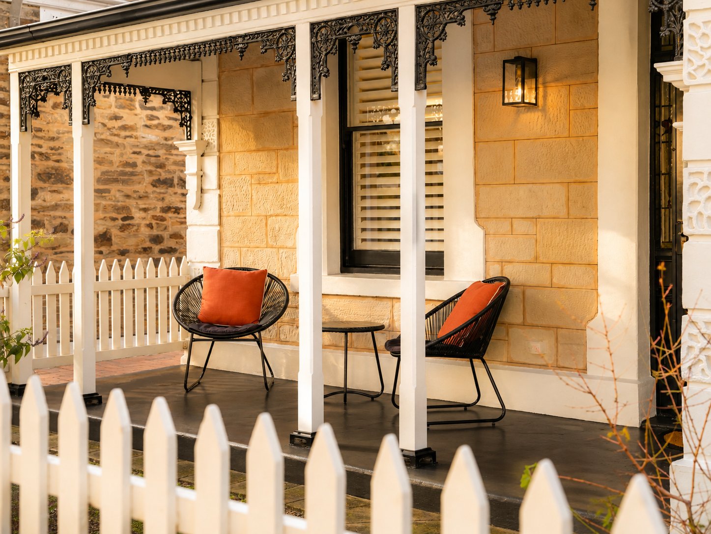 Restored sandstone verandah with cast-iron lacework and a white picket fence at 21 Norwood