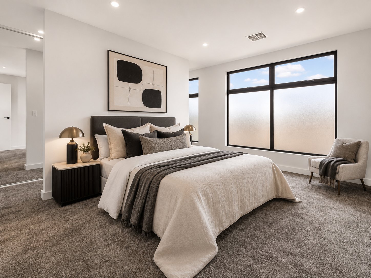 Main bedroom with upholstered bedhead, black-framed window and armchair at 1 Magill