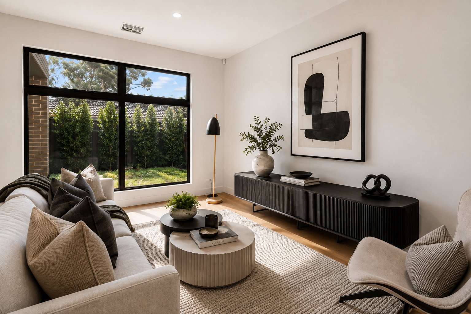 Living room with black-framed window, timber flooring and built-in joinery at 1 Magill