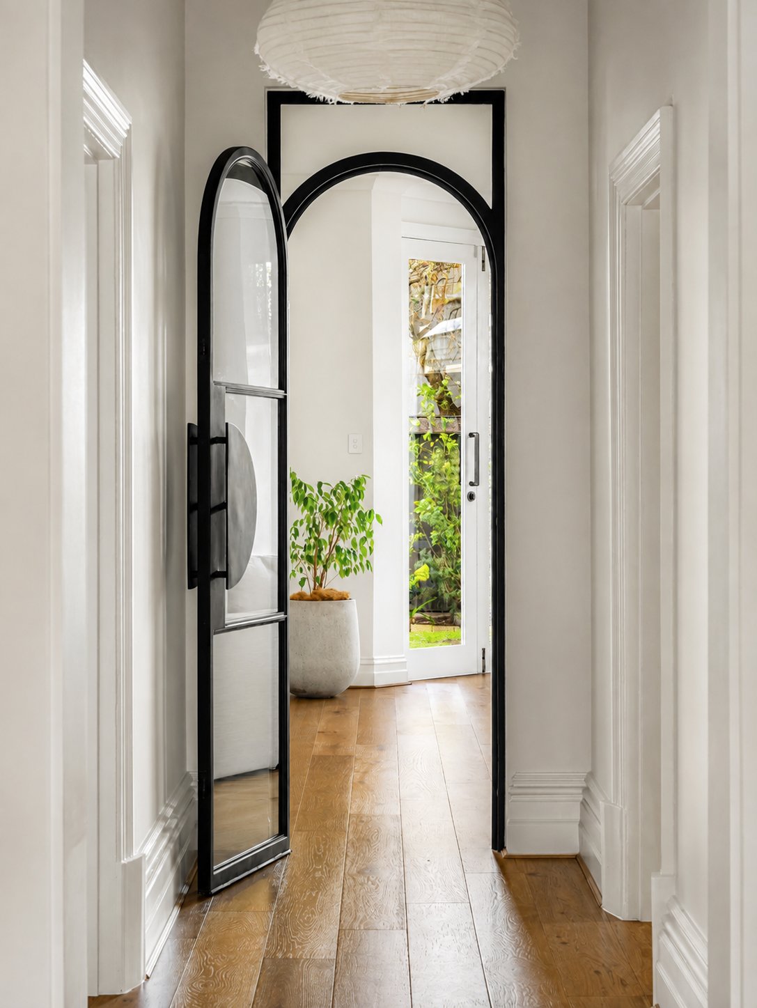 Arched hallway with a black steel-framed glass door opening to the garden at 21 Norwood