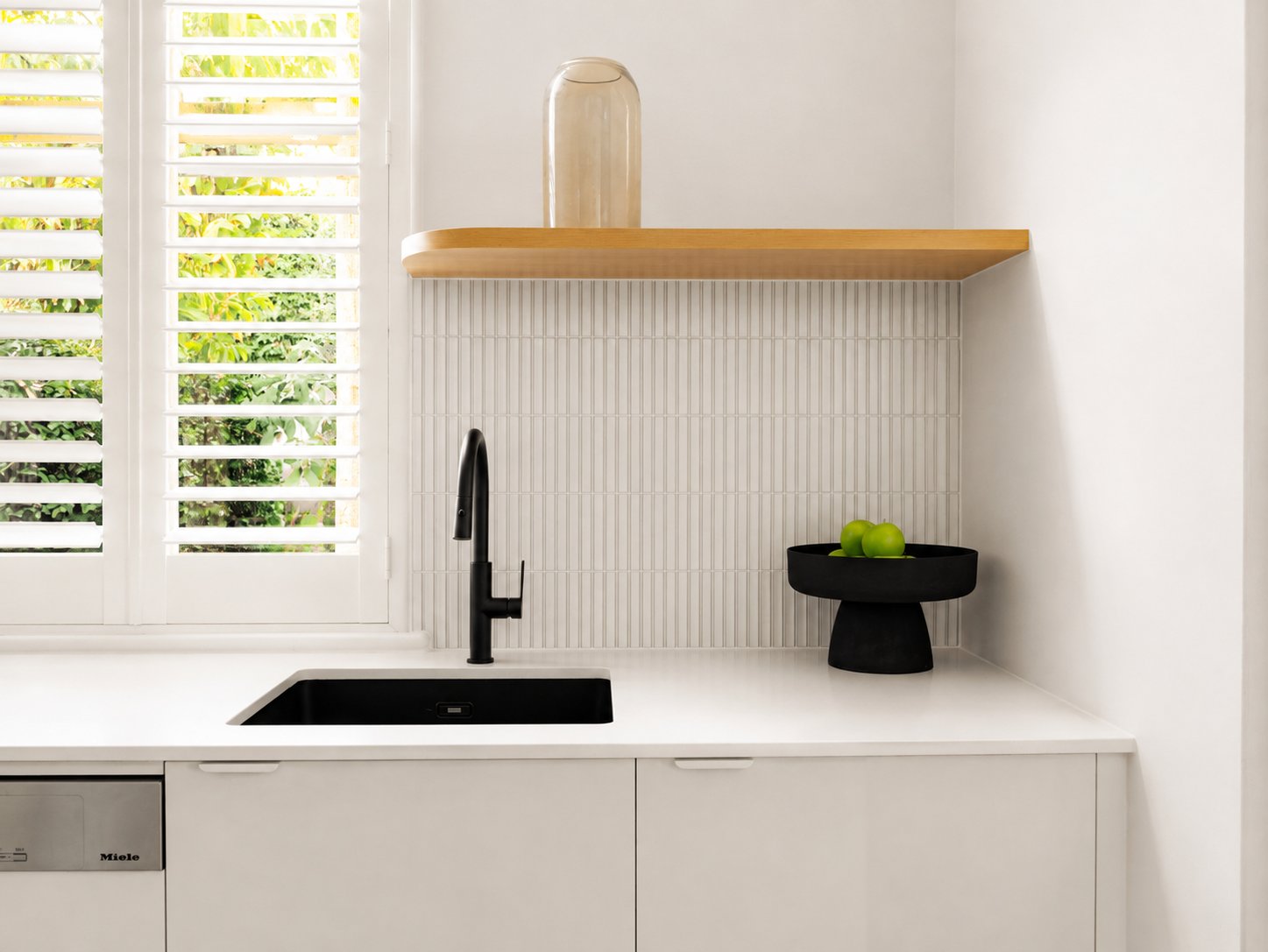 Kitchen bench with a black undermount sink, vertical tile splashback and plantation shutters at 21 Norwood