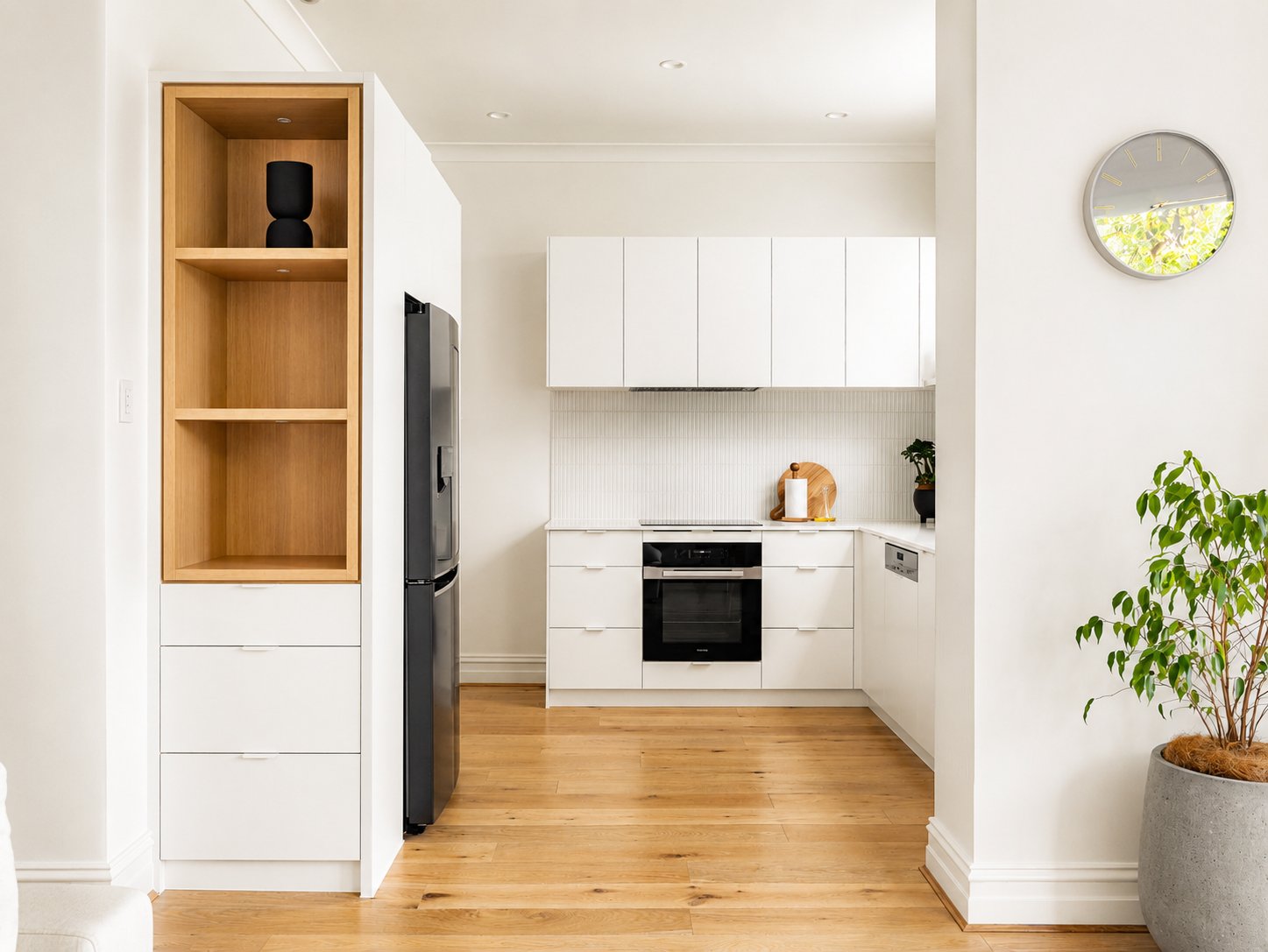 White kitchen with an oak-lined display niche, integrated refrigerator and oak flooring at 21 Norwood