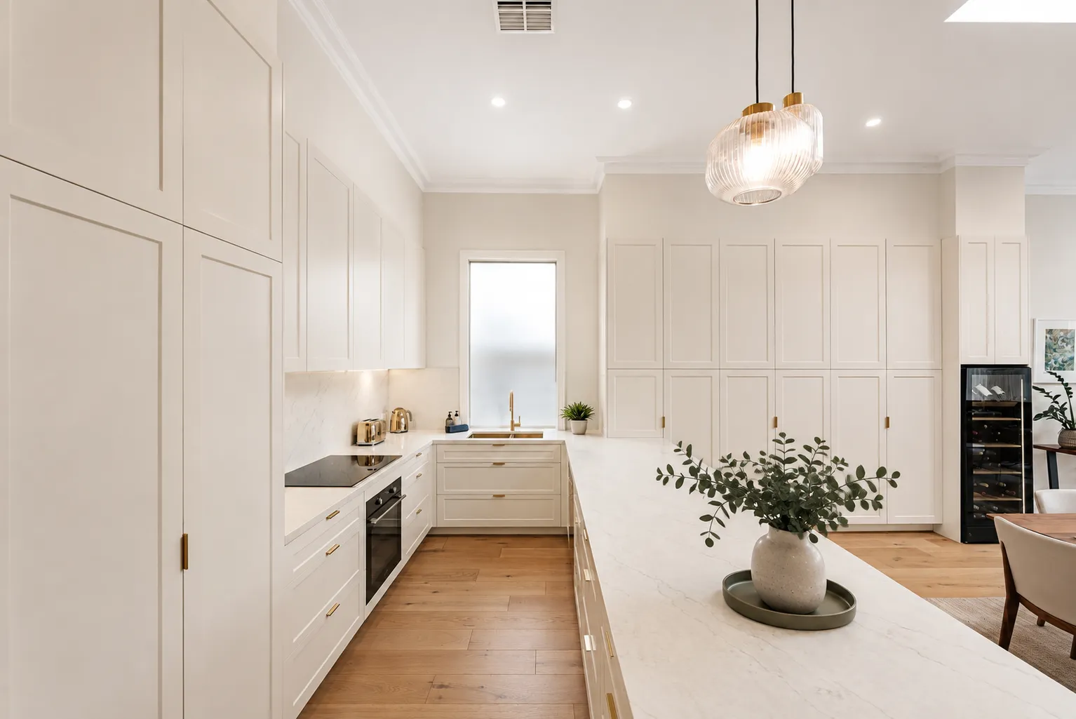Kitchen with full-height shaker joinery, stone benchtop and brass tapware at 84 Toorak Gardens
