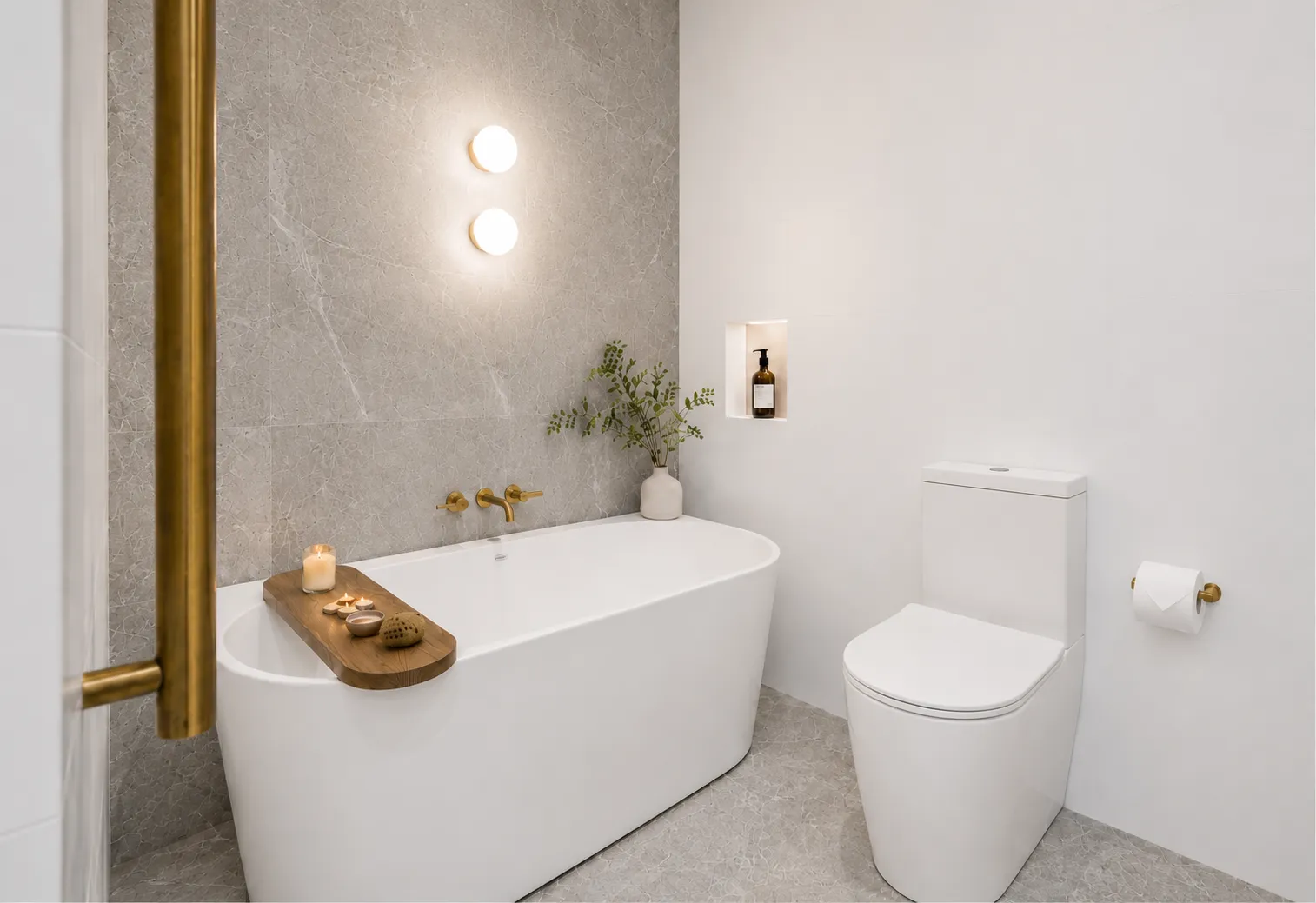 Freestanding bath against a grey stone feature wall with brass fittings at 84 Toorak Gardens