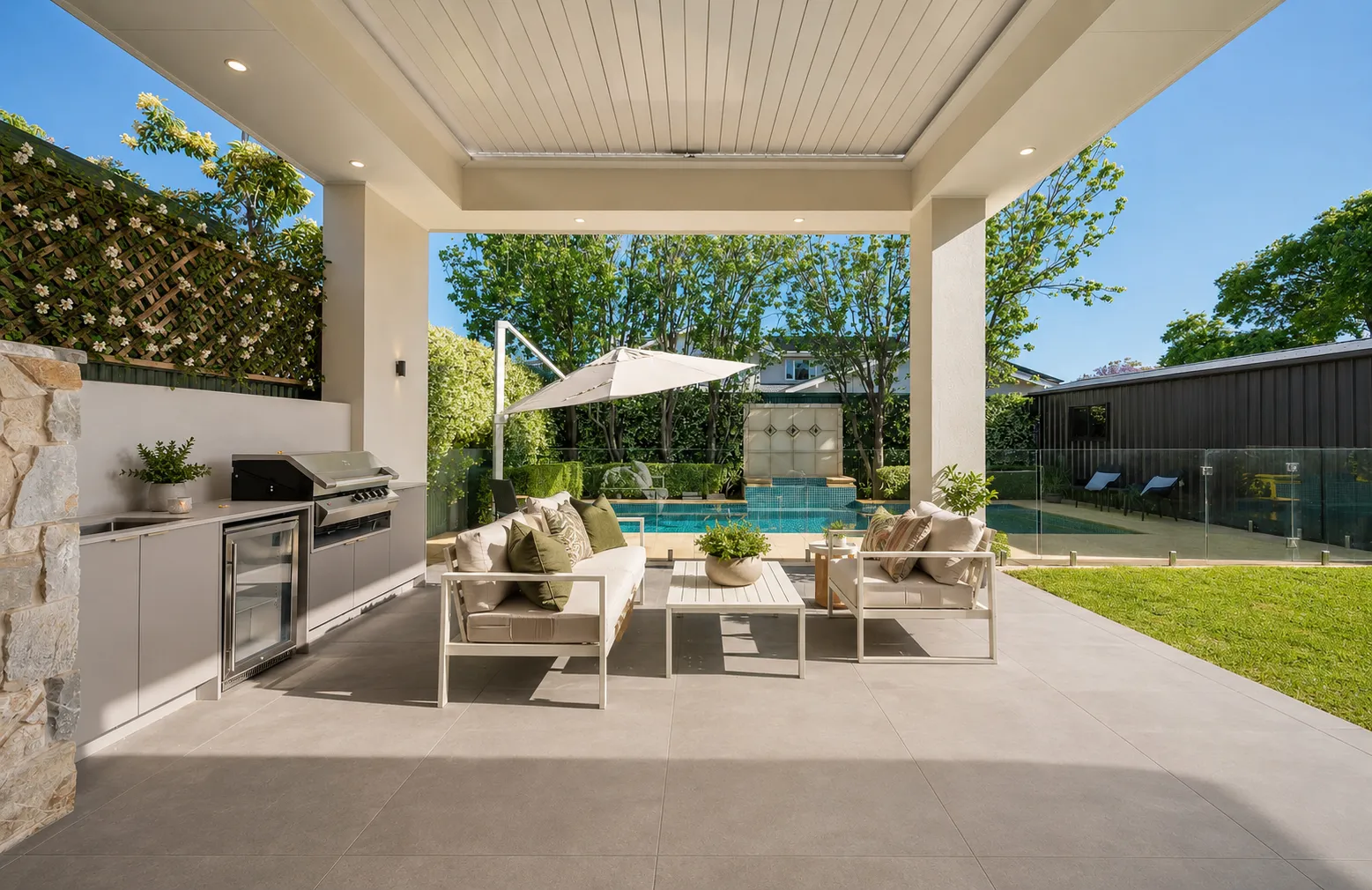 Covered alfresco with an outdoor kitchen and lounge setting looking toward the pool at 84 Toorak Gardens