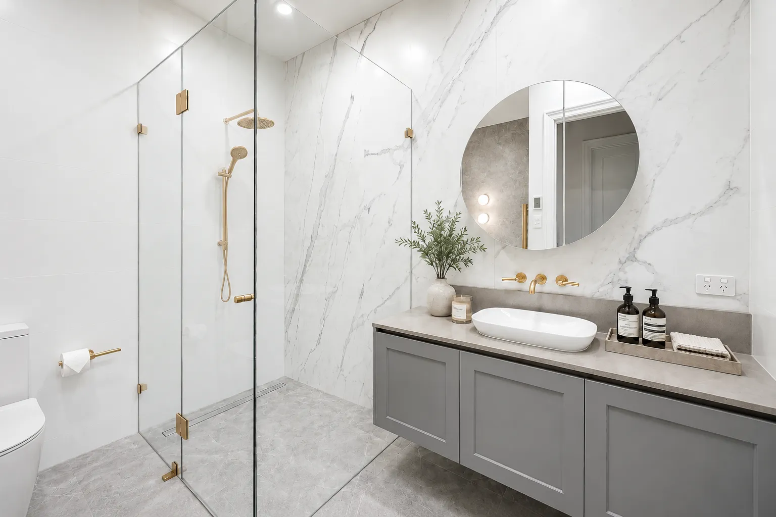 Bathroom with large-format marble-look slab walls, frameless shower and brushed brass tapware at 84 Toorak Gardens