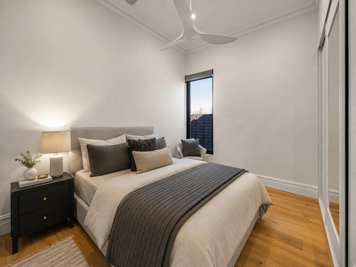 Bedroom with a ceiling fan, mirrored robes and a narrow garden window at 84 Toorak Gardens