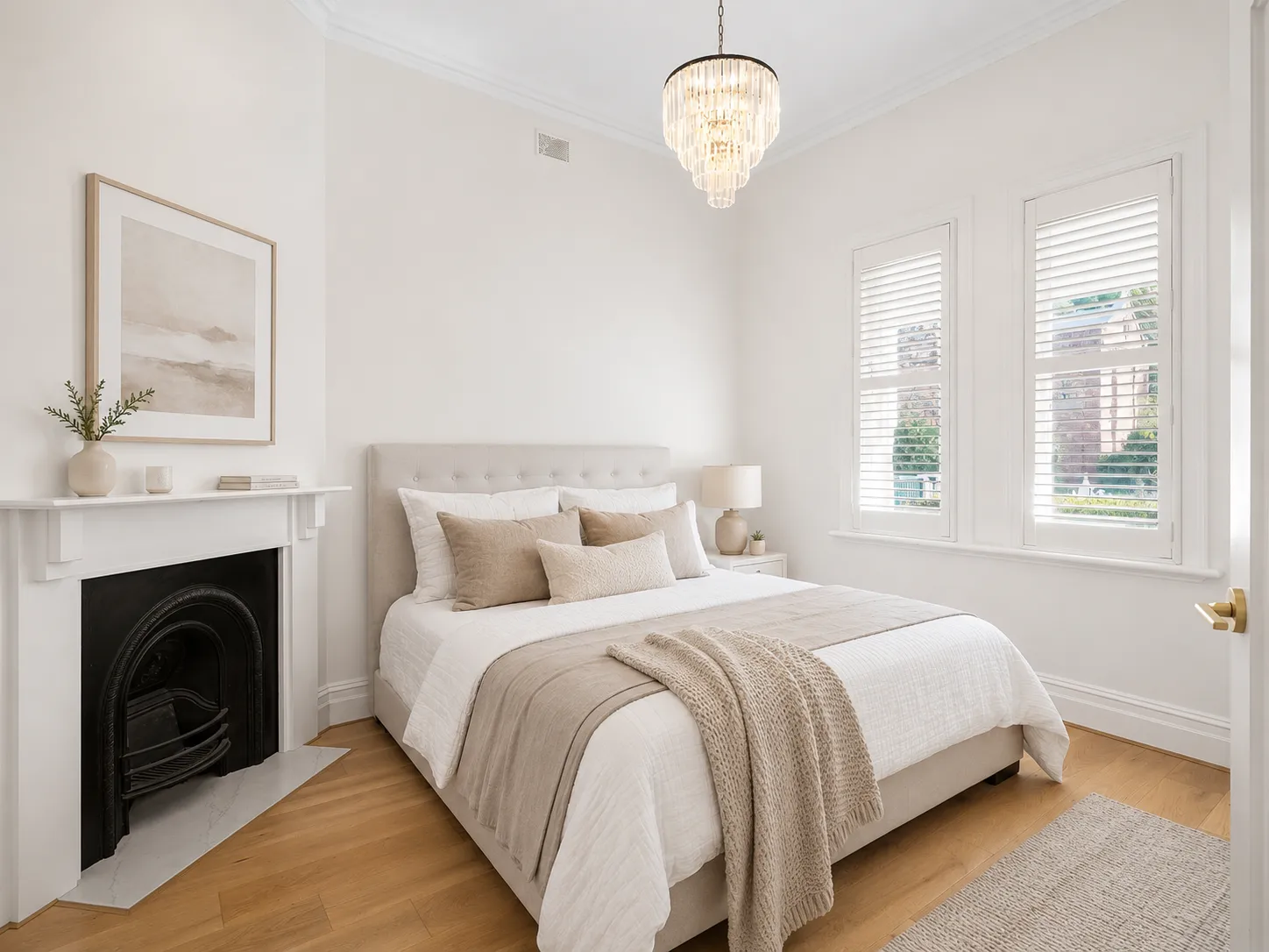 Villa bedroom with an original cast-iron fireplace, plantation shutters and a crystal pendant at 84 Toorak Gardens