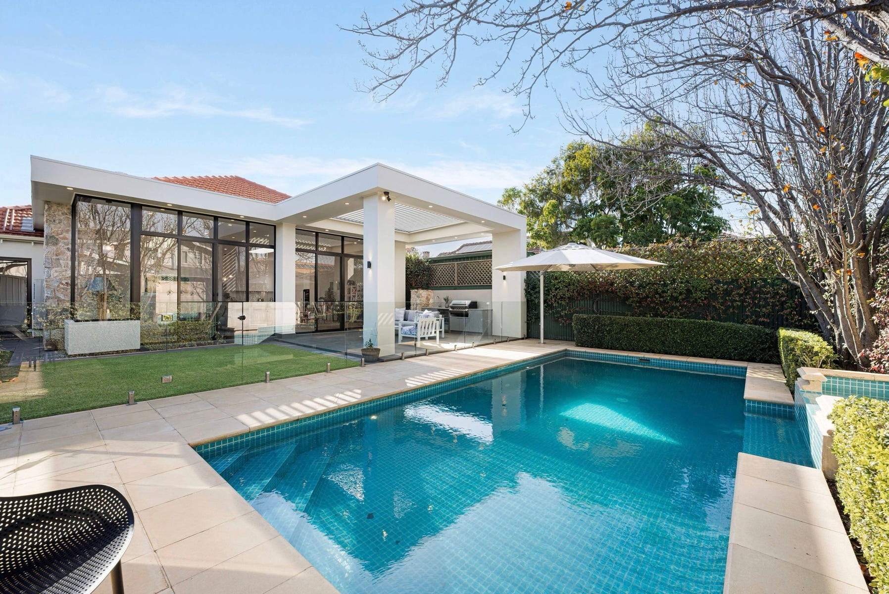 Contemporary rear extension with full-height glazing opening onto the lawn, alfresco and pool at 84 Toorak Gardens