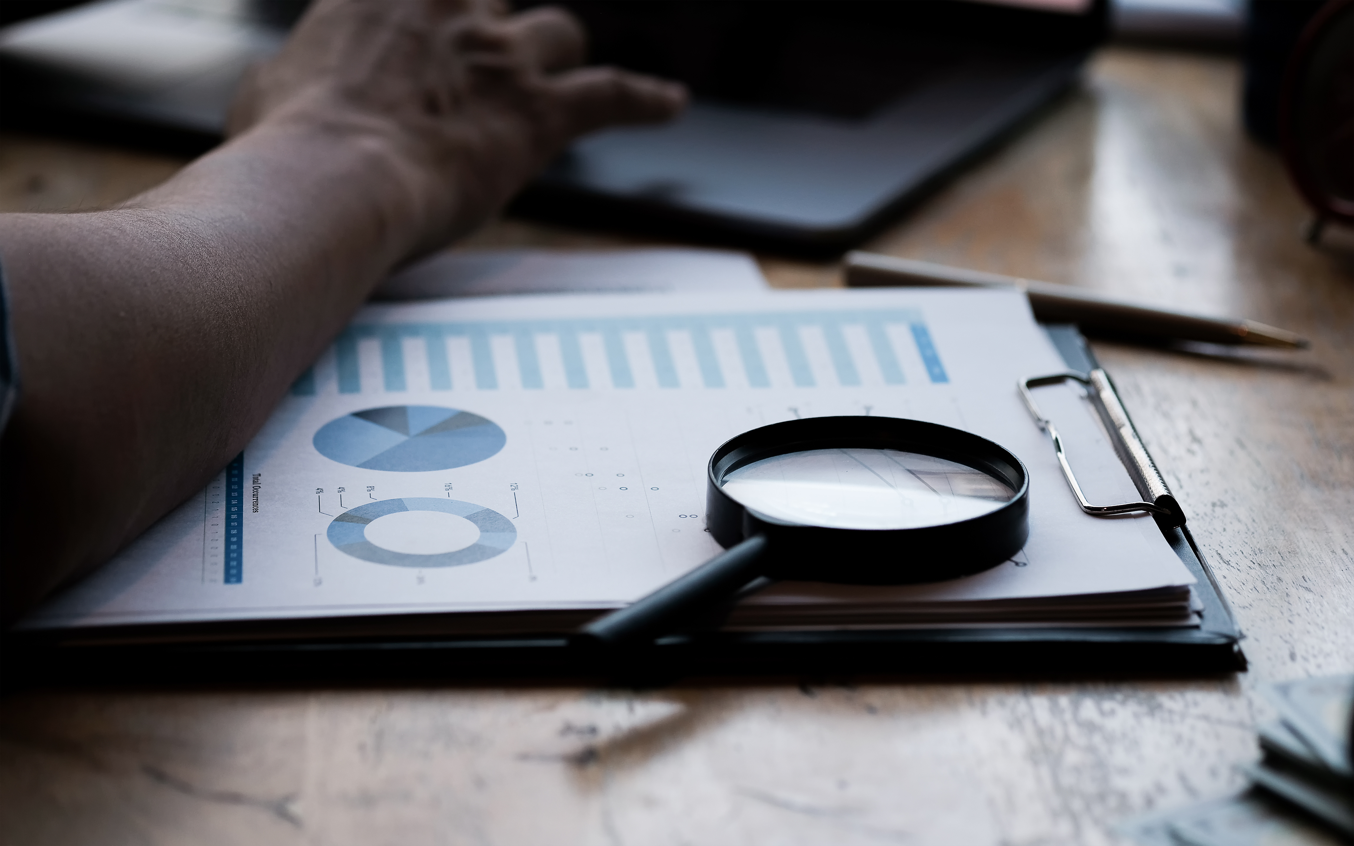 Businessman examining documents with a magnifying glass during a fraud investigation