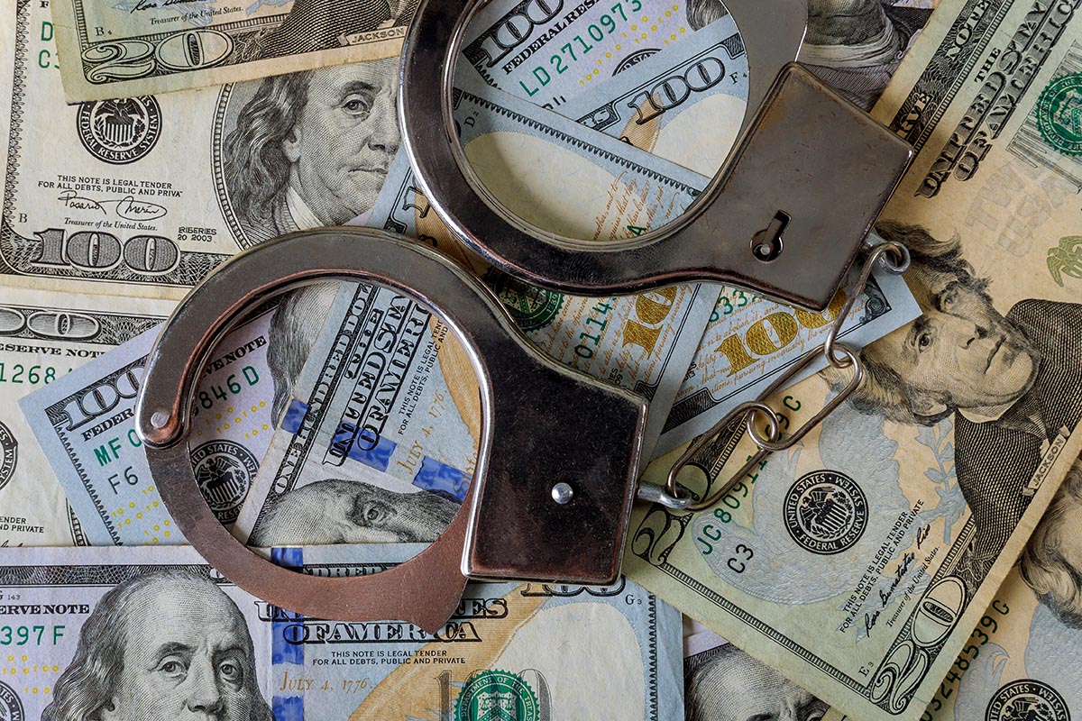 Handcuffs and seized cash representing a cryptocurrency scam-center takedown
