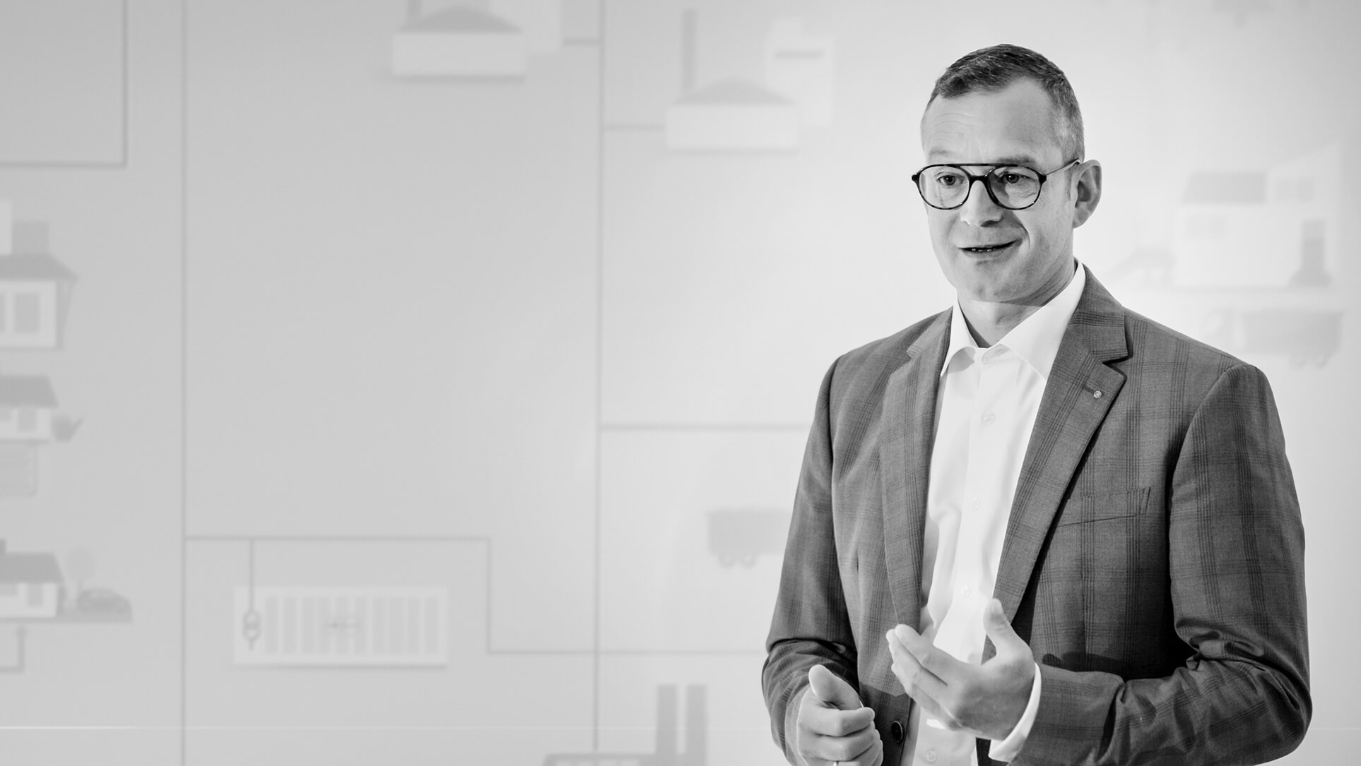 Marco Krasser steht vor einer hellen Wand und gestikuliert mit der rechten Hand.