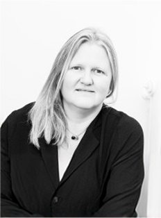 Portrait en noir et blanc d'une femme aux cheveux longs portant un blazer noir et un collier.