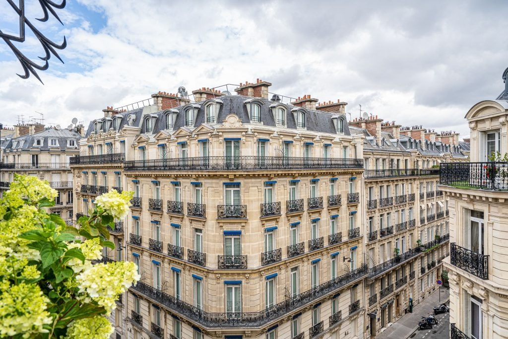 Immeuble haussmannien éclairé au coin d’une rue avec traces lumineuses de voitures la nuit à Paris.