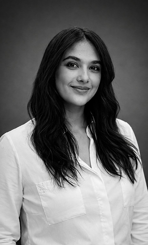 Portrait en noir et blanc d'une femme souriante aux cheveux longs et chemise blanche.