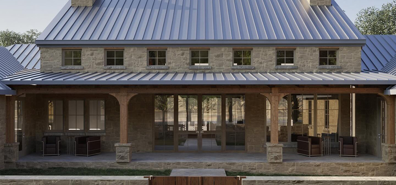 Front view of a stone house with a metal roof and wooden porch pillars with outdoor seating.