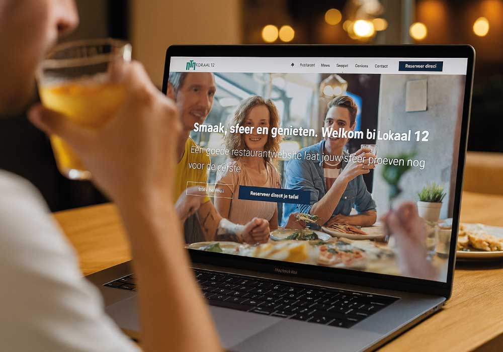 Iemand drinkt van een glas terwijl hij naar een restaurantwebsite met vrienden kijkt op een laptop.