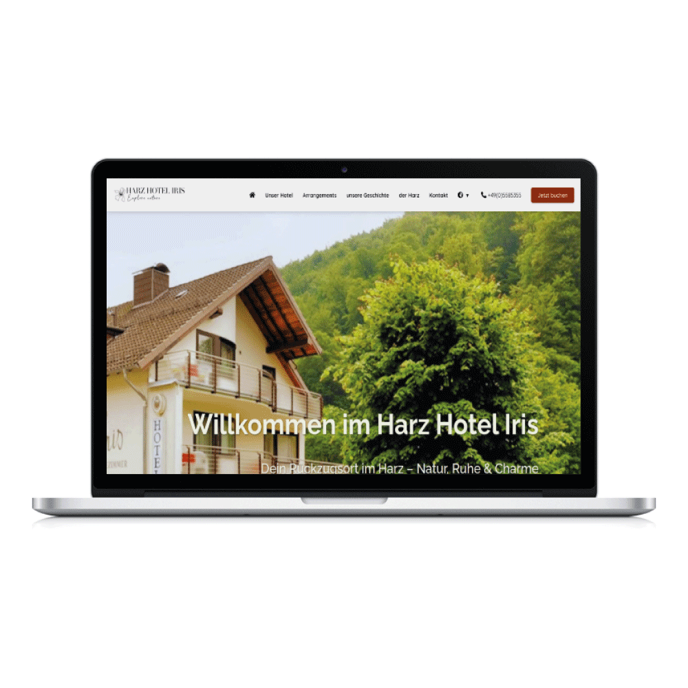 Laptop toont website met welkom bij Harz Hotel Iris en een huis naast groene bomen.