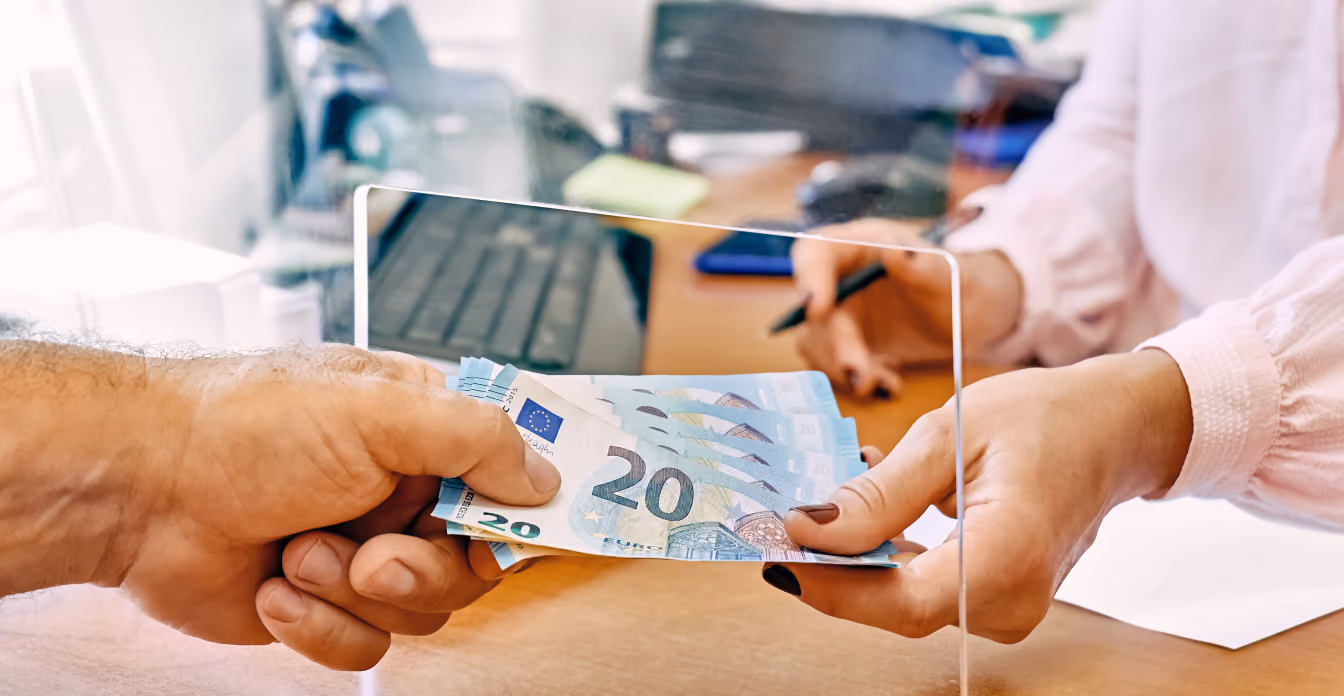 Entrega de várias notas de 20 euros pela janela de vidro em um ambiente de escritório.