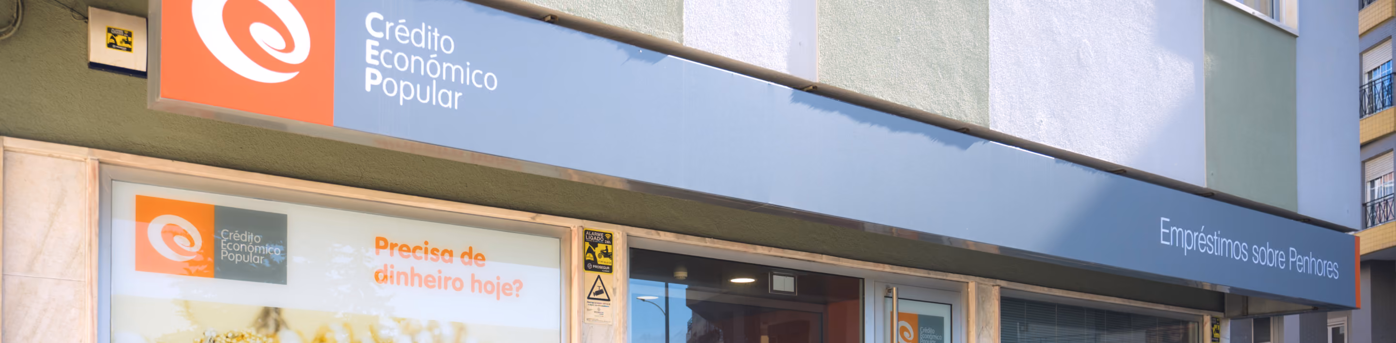 Fachada de agência de crédito com anúncio oferecendo dinheiro e empréstimos sobre penhores.