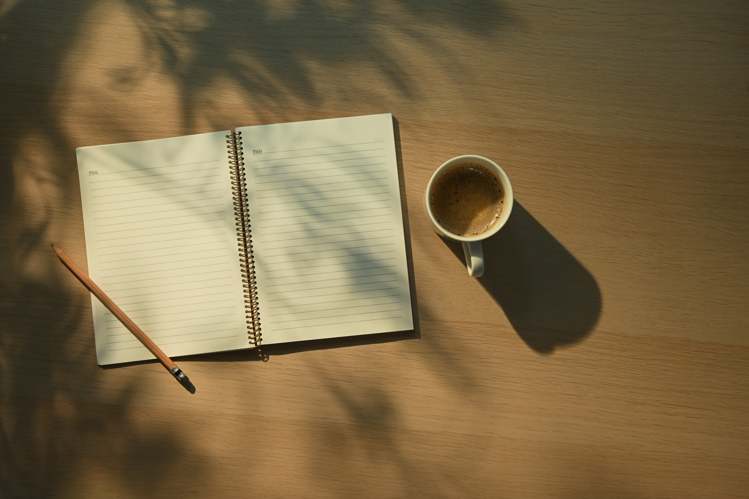 Offenes Notizbuch und eine Tasse auf einem Tisch im warmen Morgenlicht