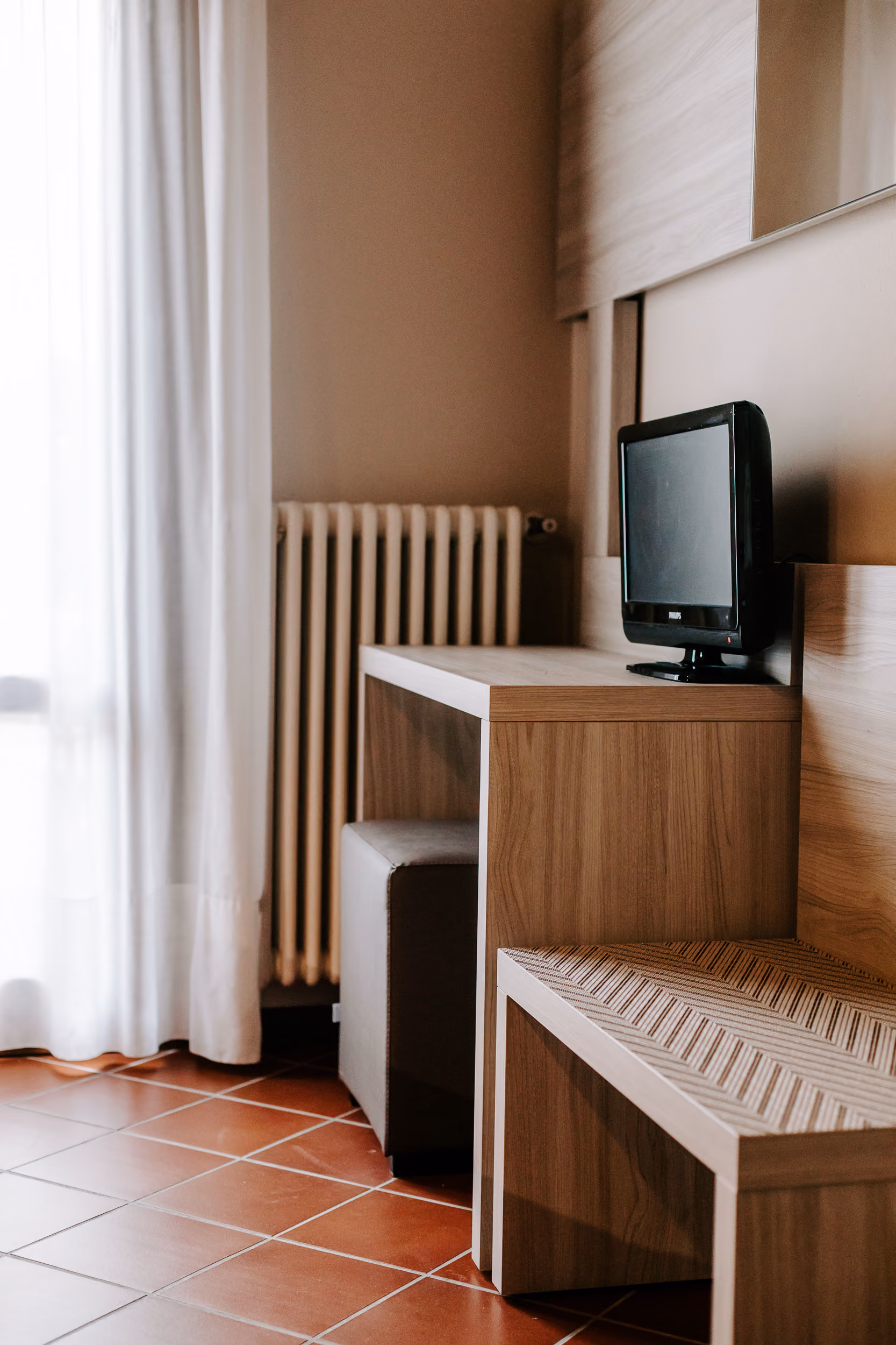 Zona scrivania in legno chiaro e TV a schermo piatto in camera da letto per viaggi di lavoro.