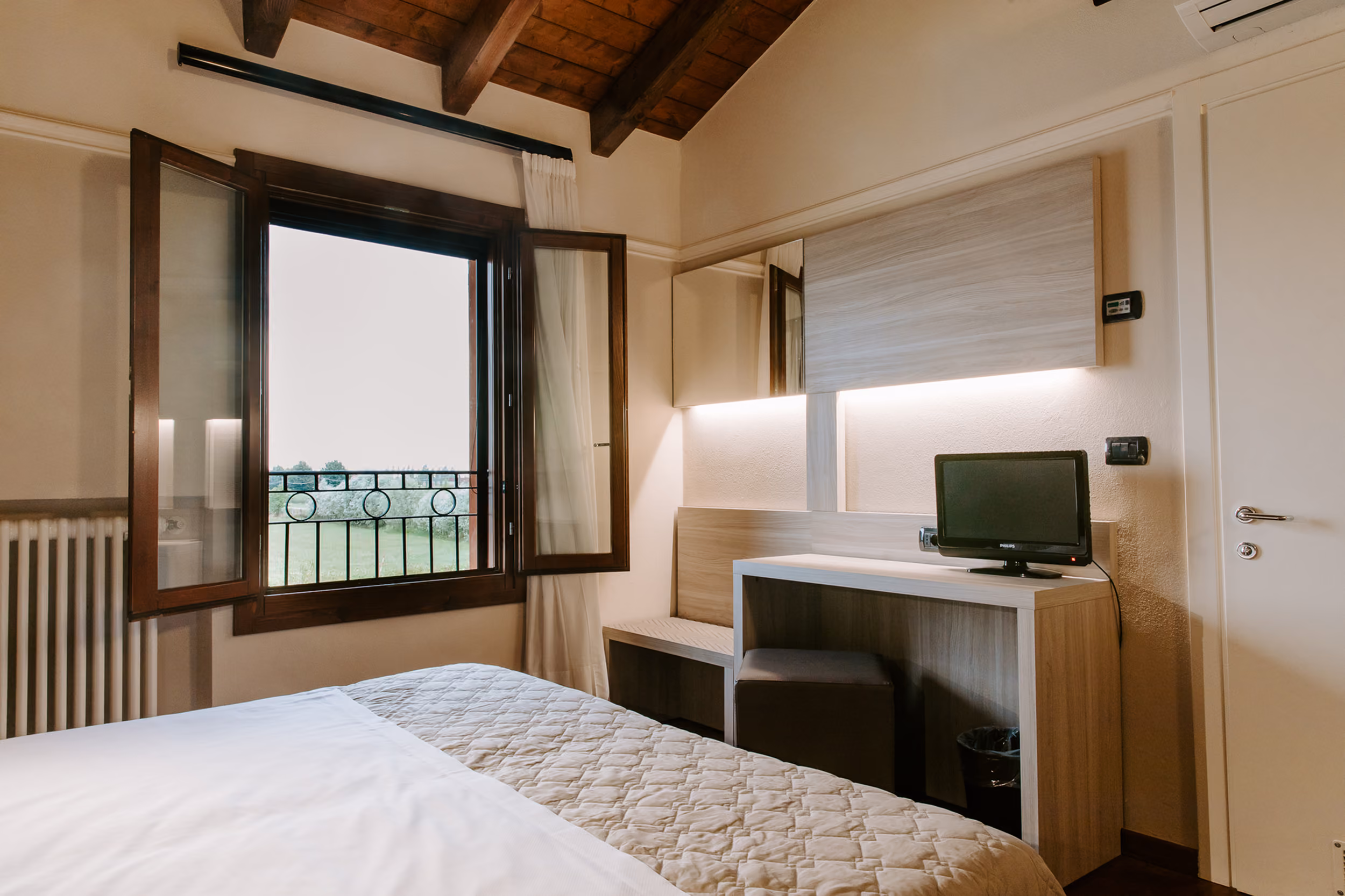 Zona scrivania e sedia per smart working in camera da letto luminosa con vista giardino.