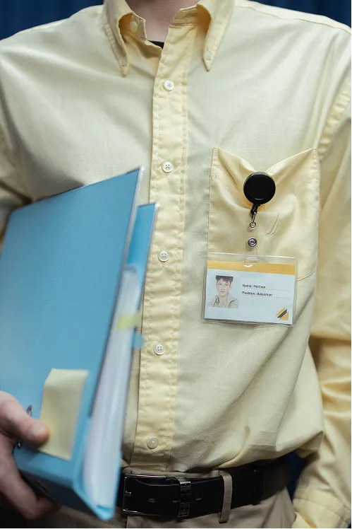 Collaborateur portant un badge d'identification et tenant une pochette de documents
