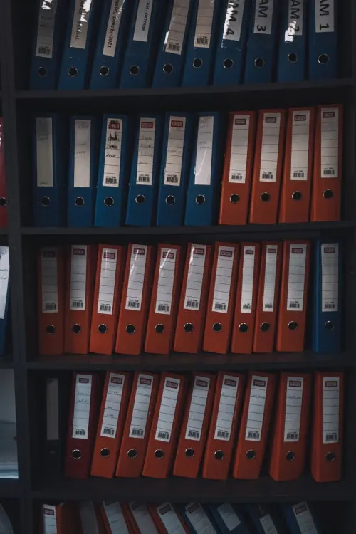 Rayonnages d'archives remplis de classeurs à levier rouges et bleus étiquetés