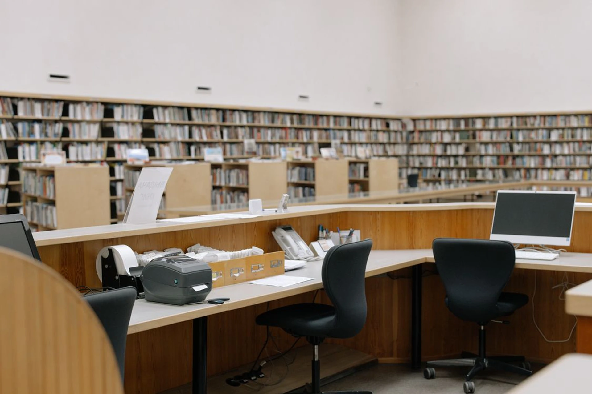 Salle de bibliothèque avec postes de travail, imprimante et rayonnages de livres