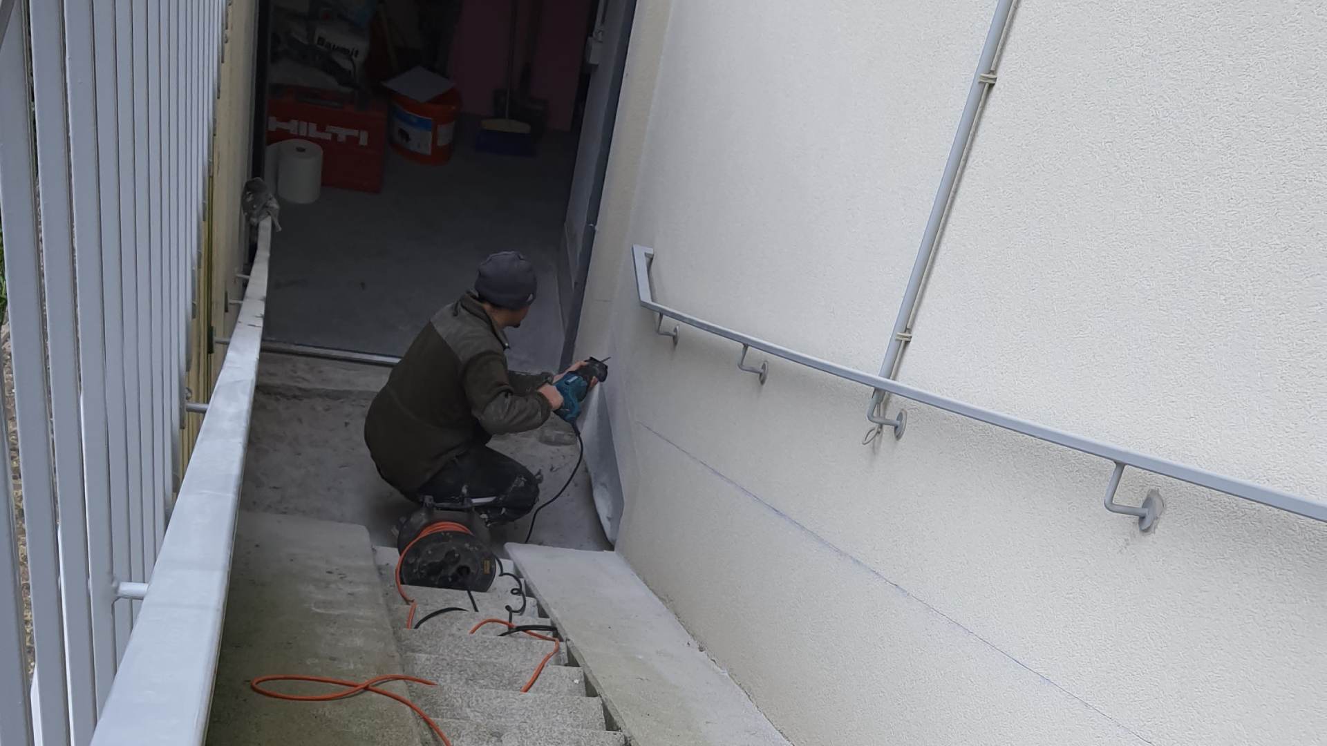 Arbeiter führt präzise Arbeiten an der Fassade im Zuge einer Sockelsanierung durch