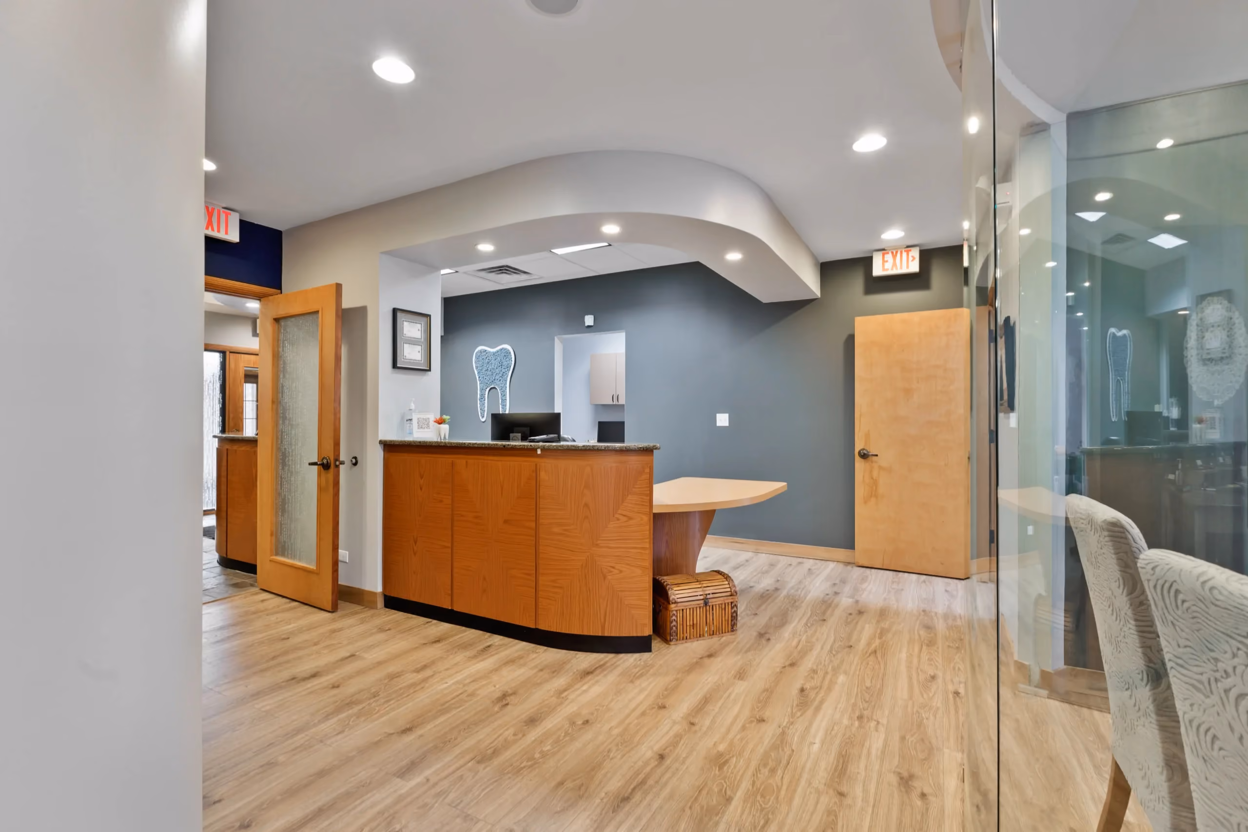 Reception area with wooden desk, gray wall featuring a tooth design, and light wood flooring.