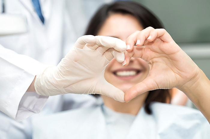 Medical professional and patient forming a heart shape with their hands in a clinical setting.