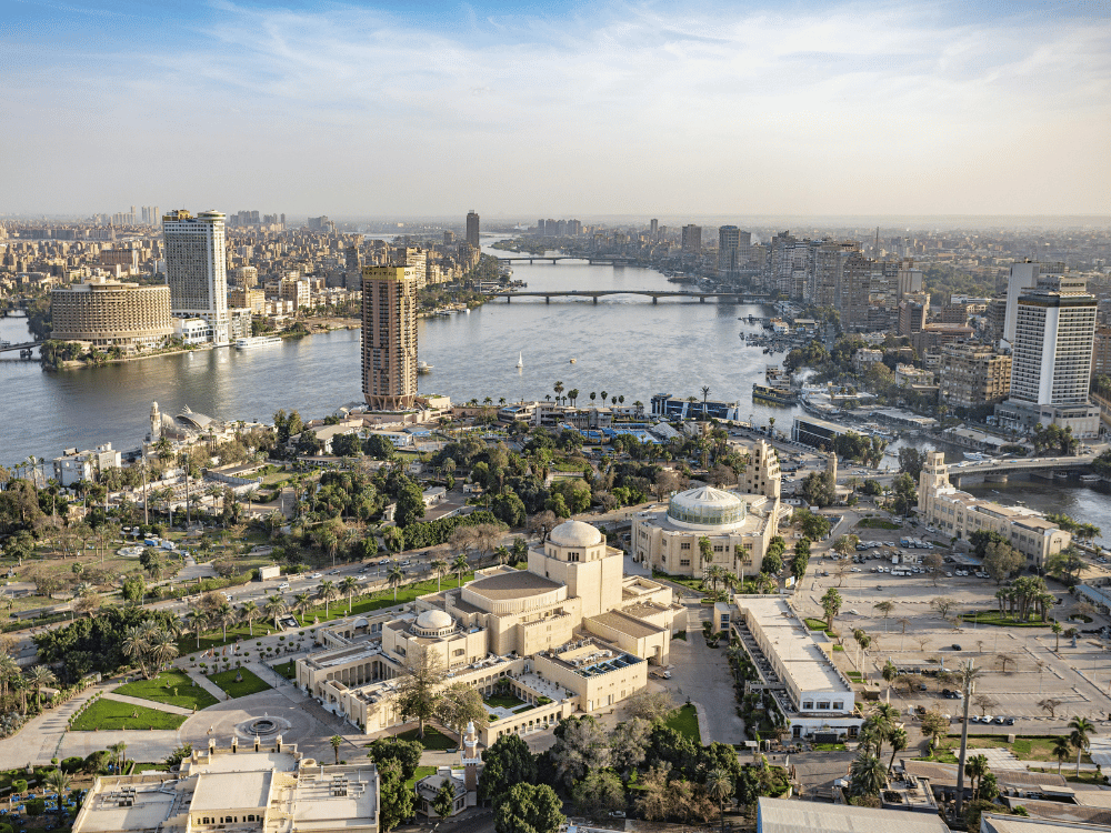 Aerial view of a city new Cairo city, bridges, tall buildings, green parks, and clear blue sky.