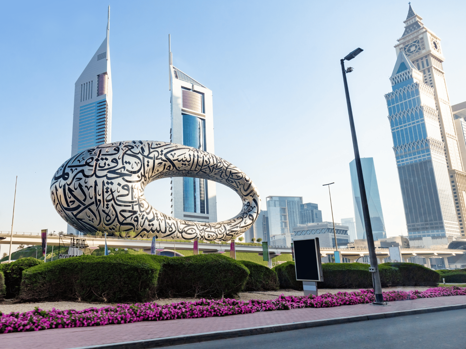 Museum of the Future with Arabic calligraphy sculpture in foreground and city skyscrapers behind in Dubai.