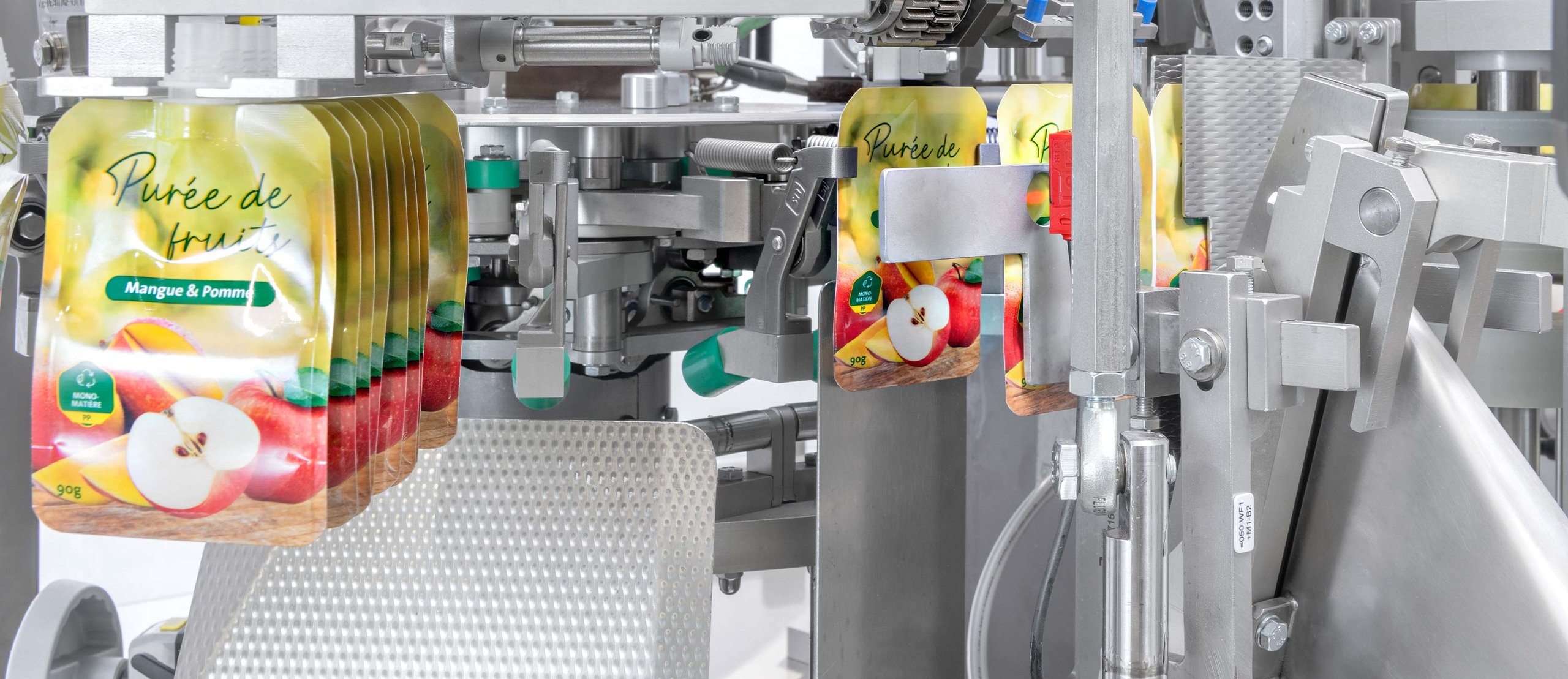 Packaging machine with hanging mango and apple puree fruit pouches in a production line.