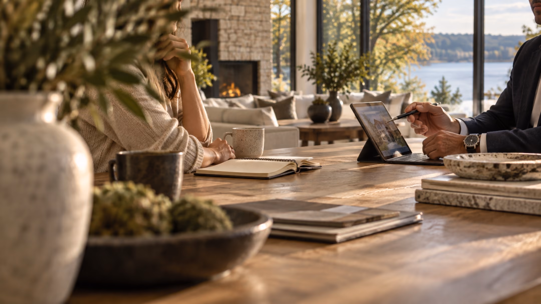 Two people reviewing and signing a document at a lakefront dining table